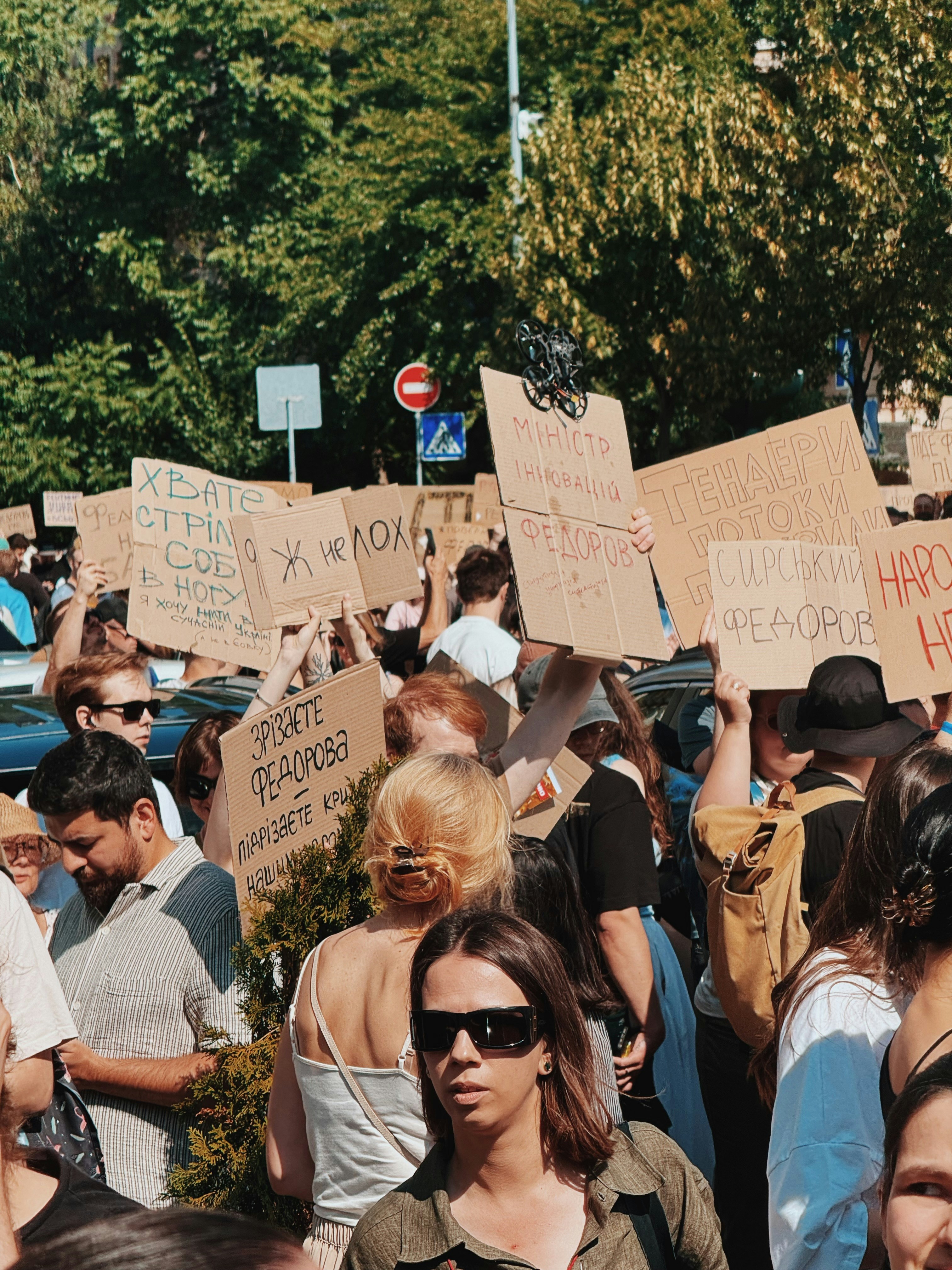 People holding protest signs at an outdoor demonstration.