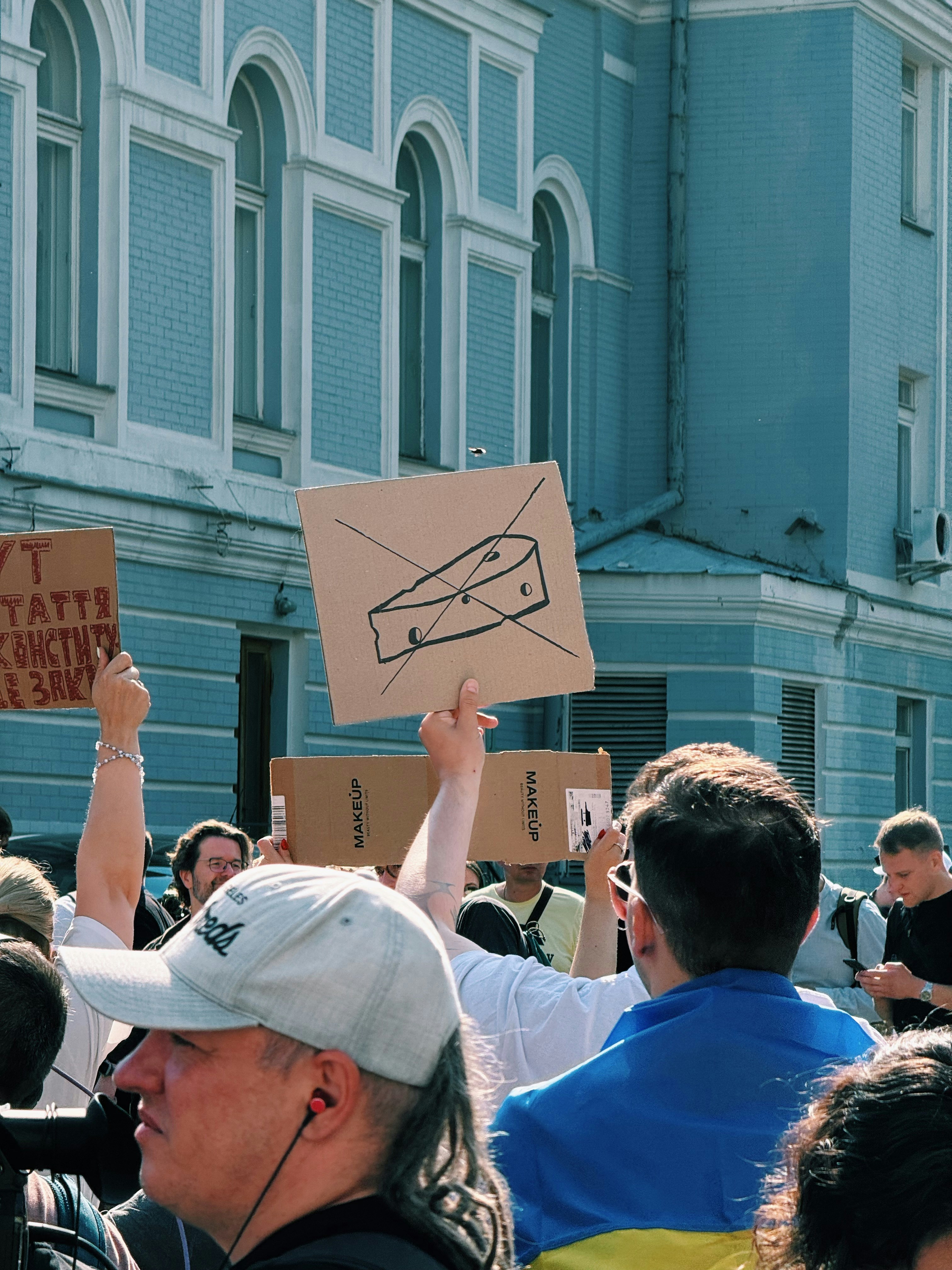People protest holding a sign with a crossed-out cheese wedge.