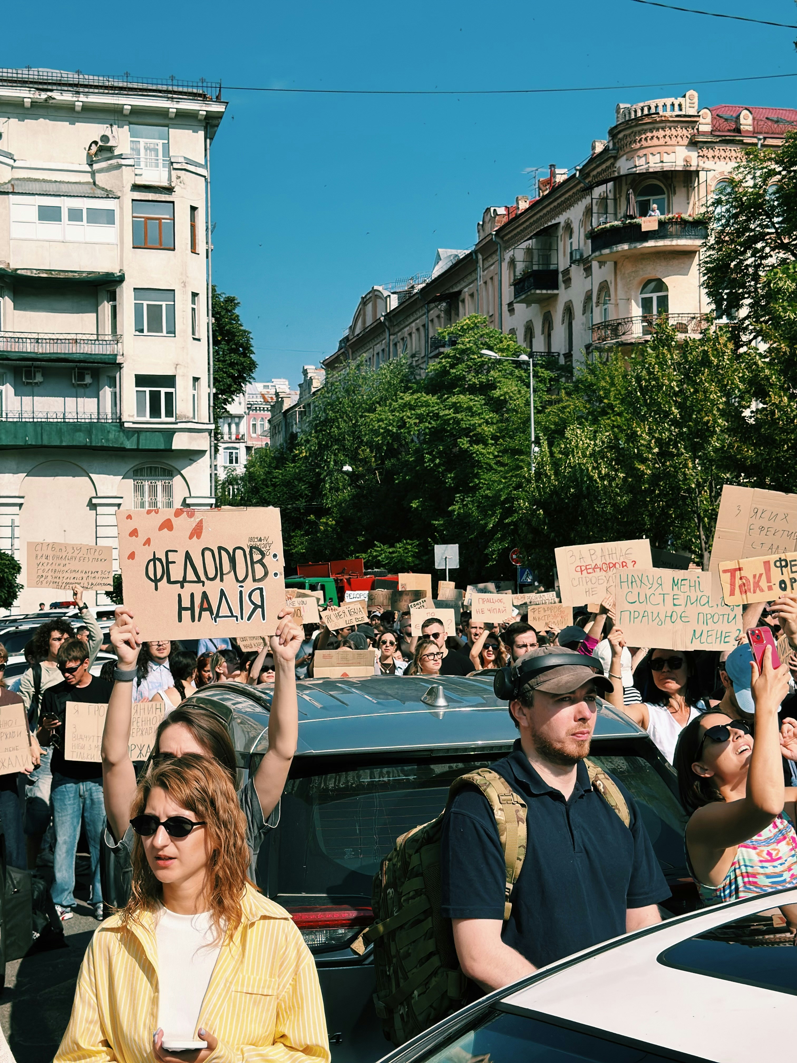 Urban protest with people holding signs under a clear sky.