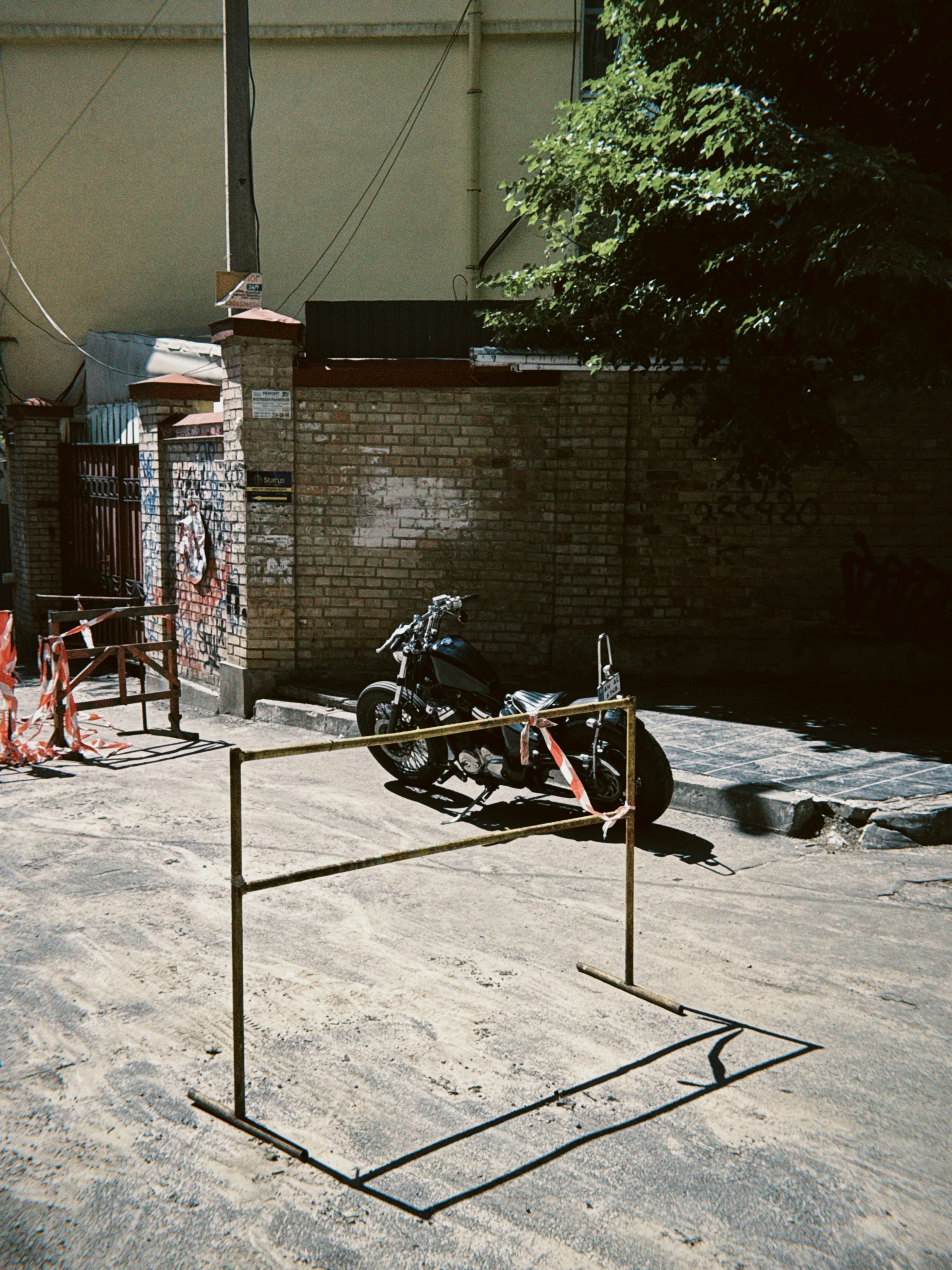A motorcycle parked behind a barrier on a sunny street.