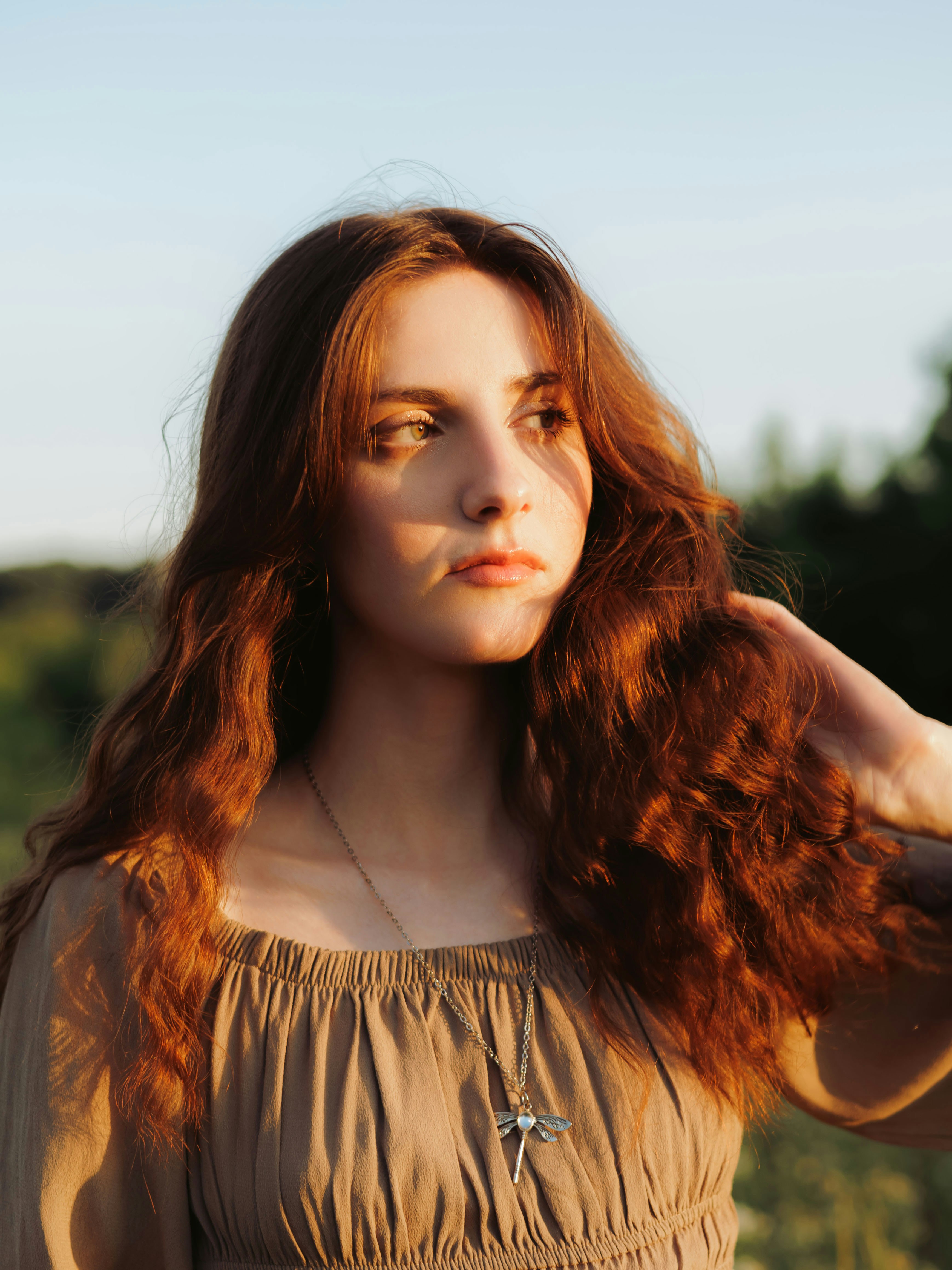 Junge Frau mit langen Haaren, getaucht in goldenes Sonnenlicht.