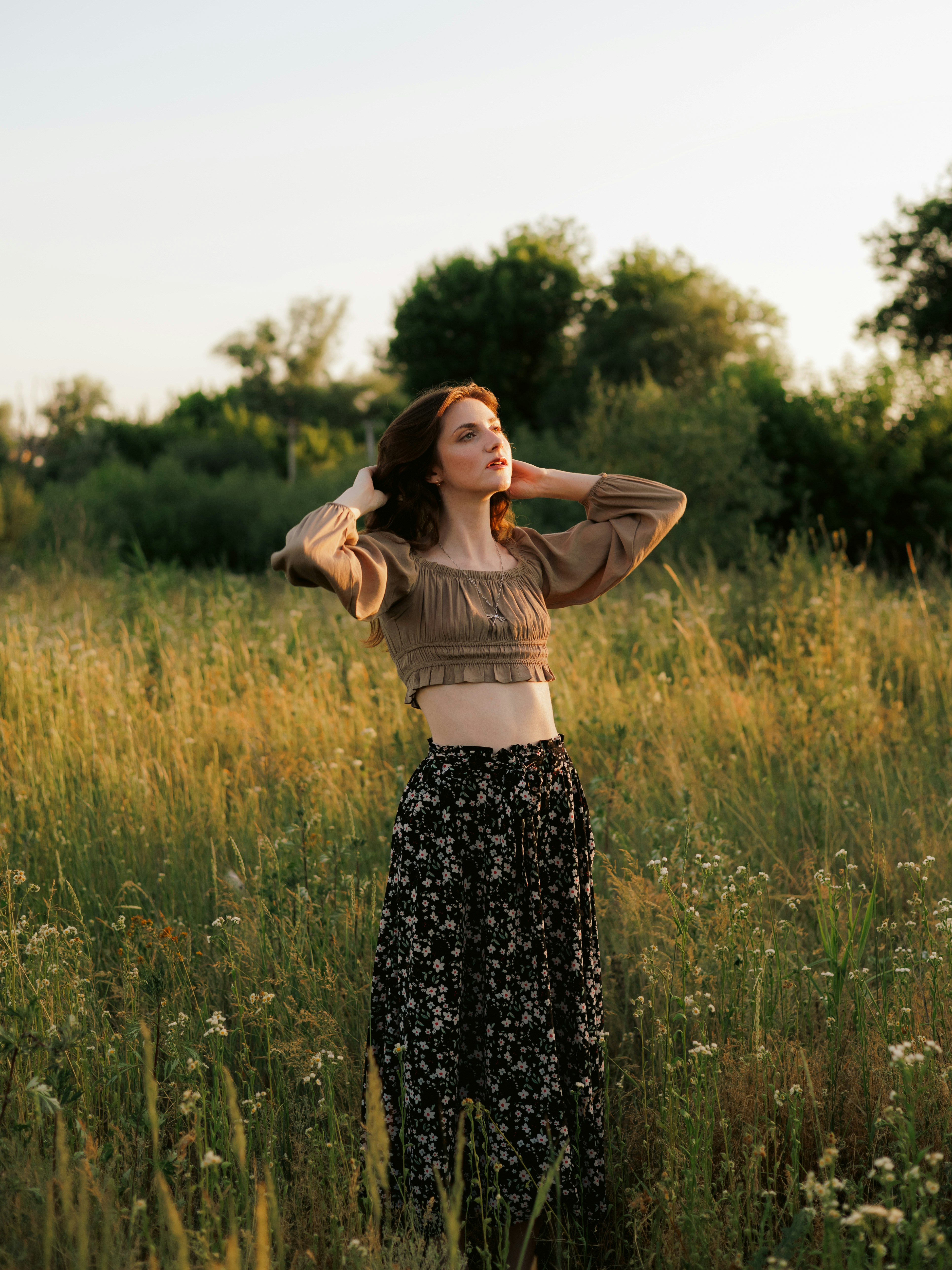 Junge Frau, die bei Sonnenuntergang auf einem goldenen Feld posiert.