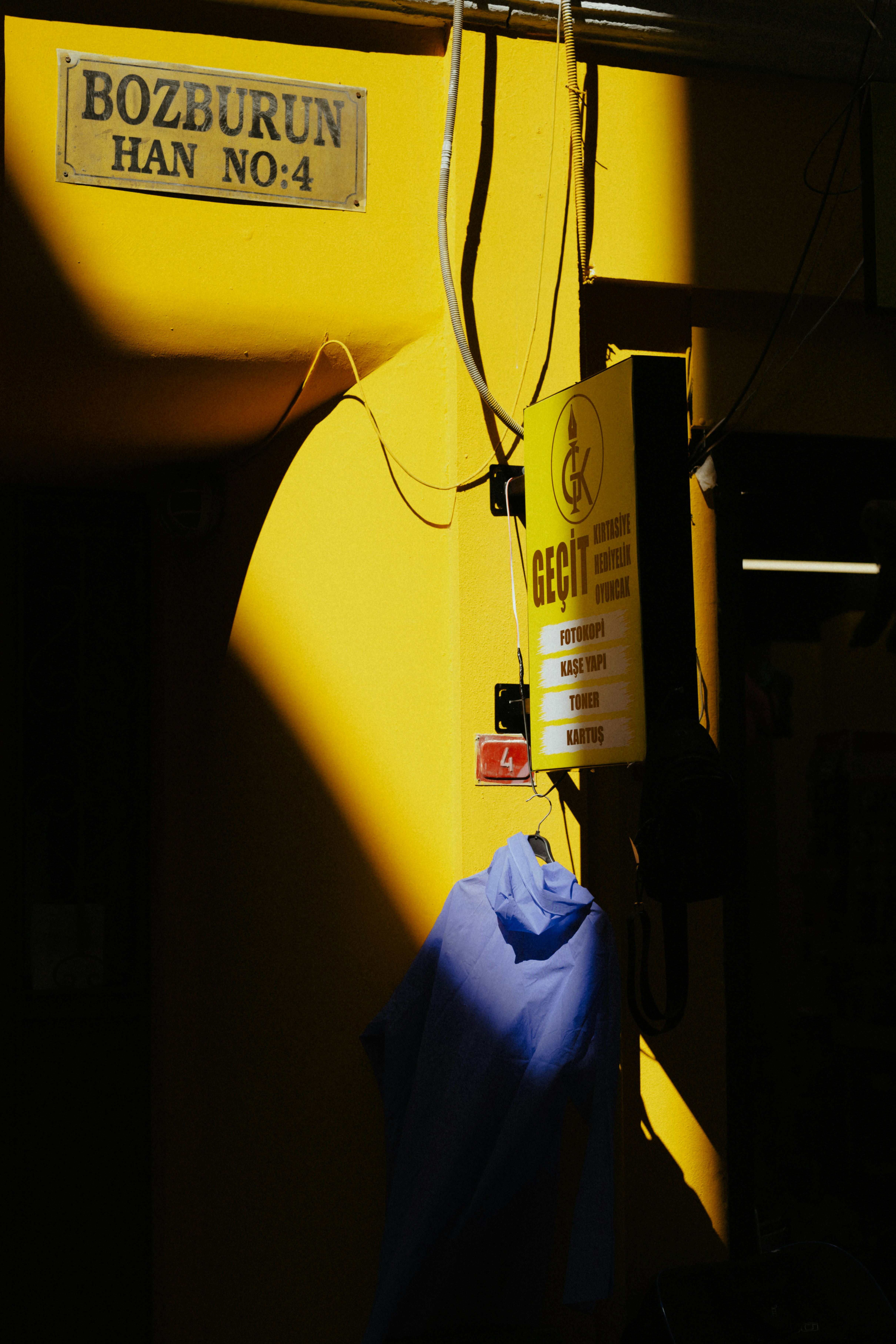 Blue jacket on sunlit yellow wall with signs.