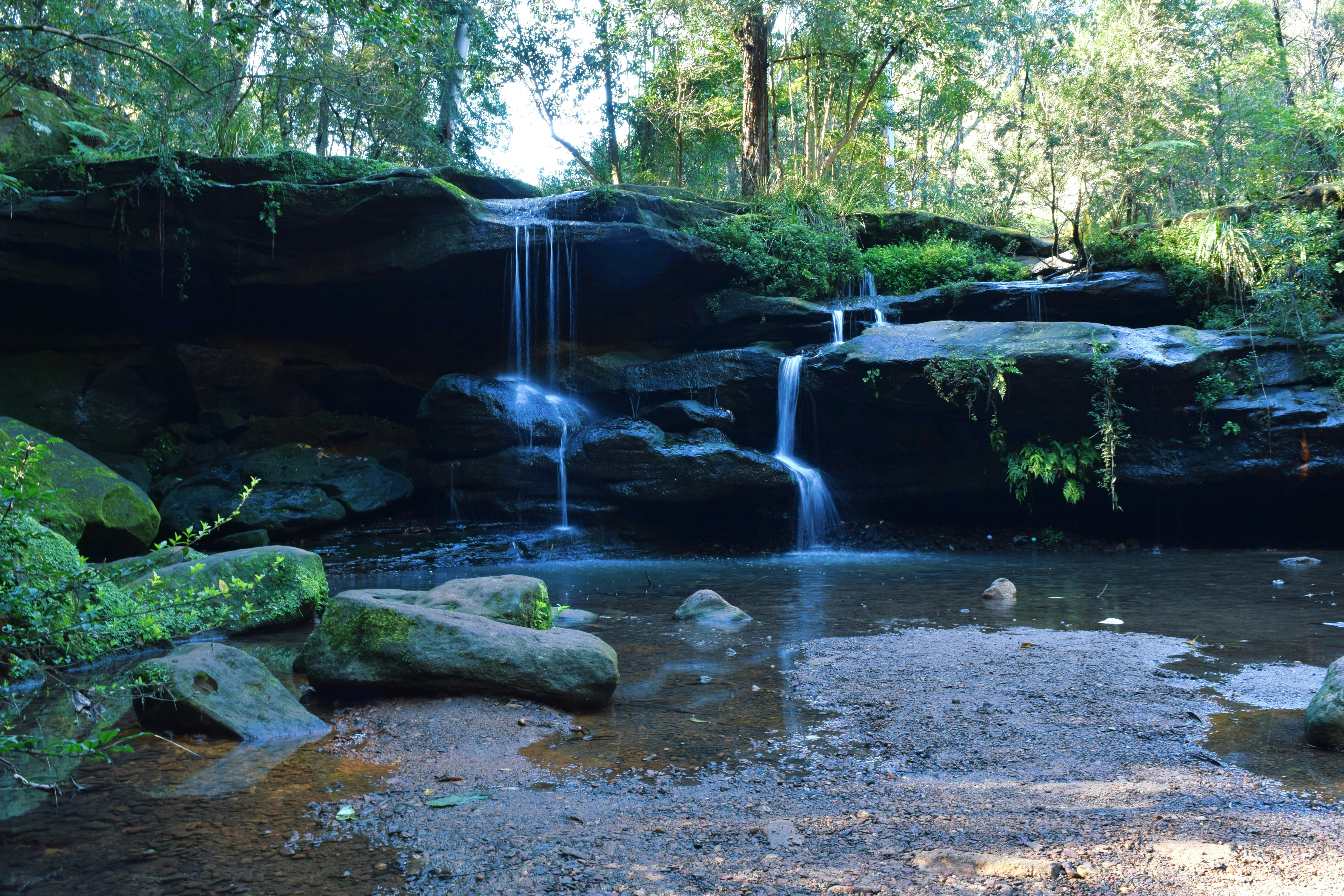Ein kleiner Wasserfall stürzt über moosige Felsen in ein ruhiges Becken.