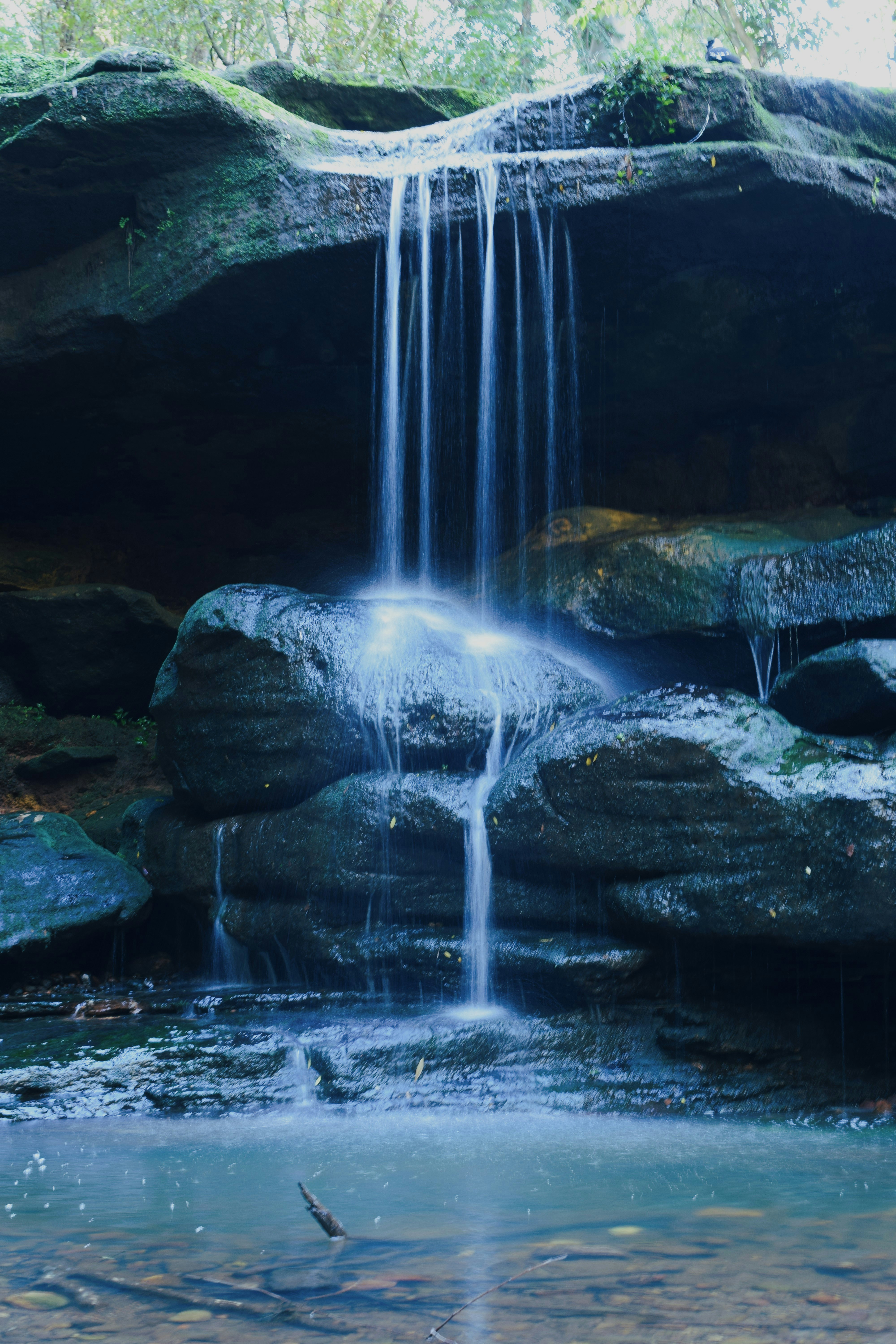 Ein kleiner Wasserfall fließt über Felsen in ein klares Becken.