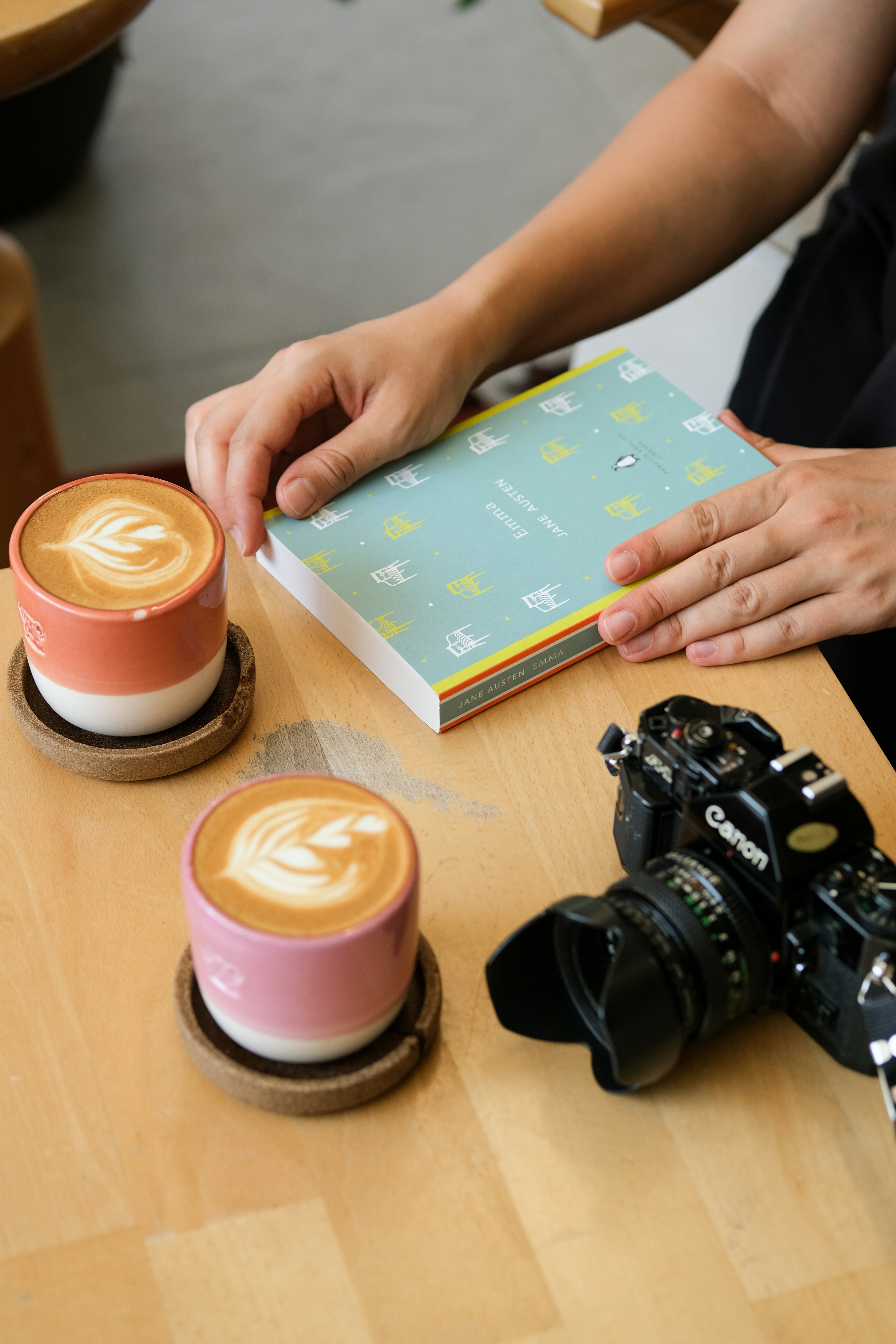 Mains tenant un livre, un latte art et un appareil photo vintage