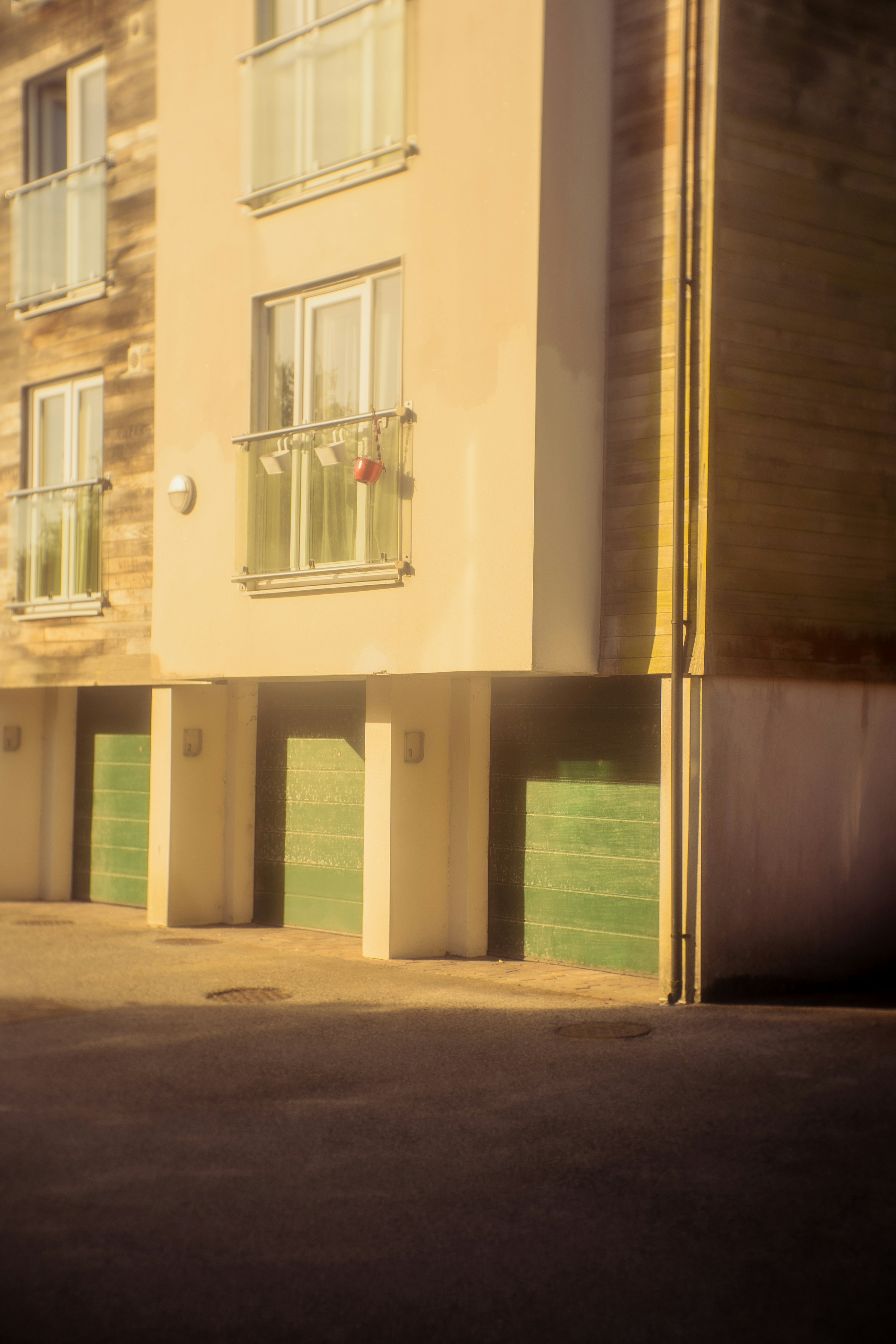 Edificio moderno con balcones y puertas de garaje verdes.