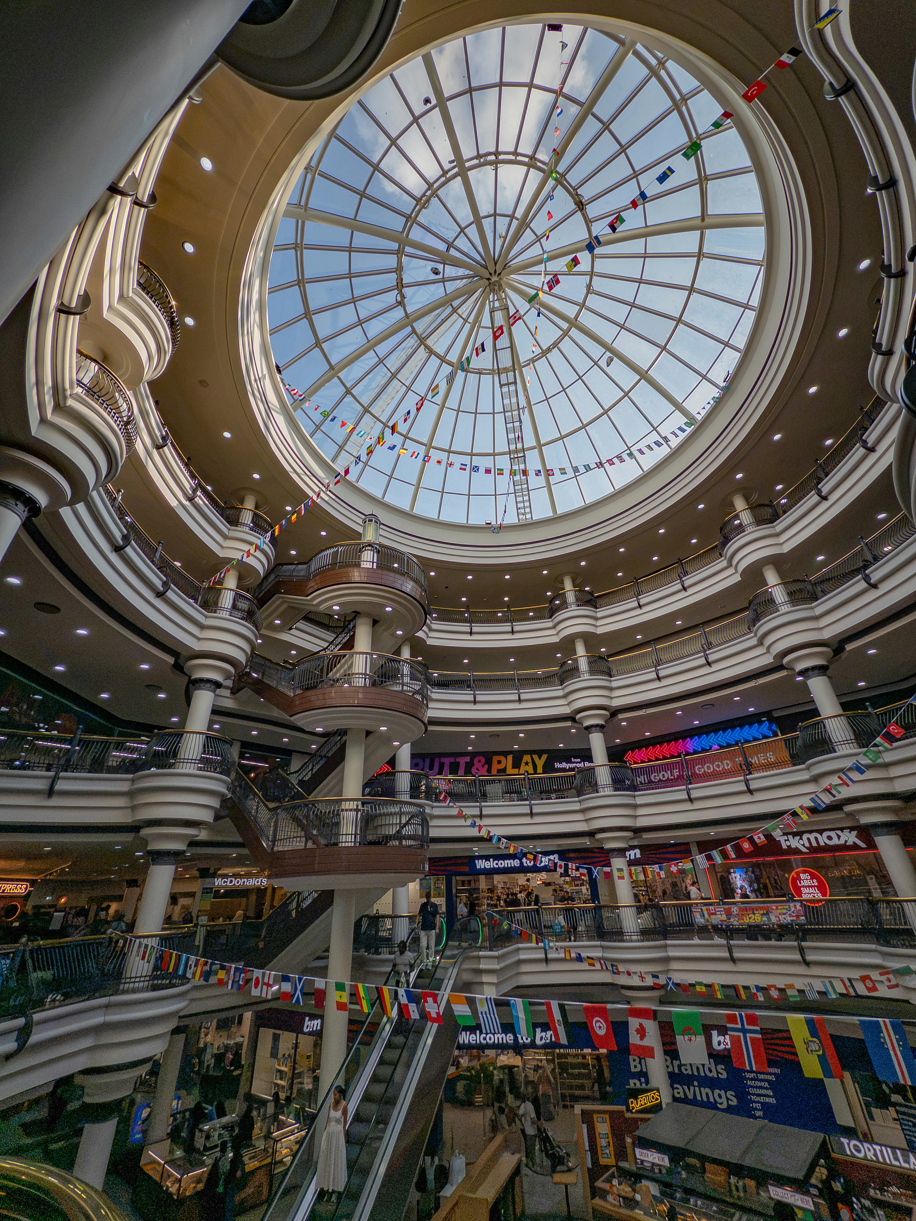 Multi-level shopping mall interior with a large glass skylight.
