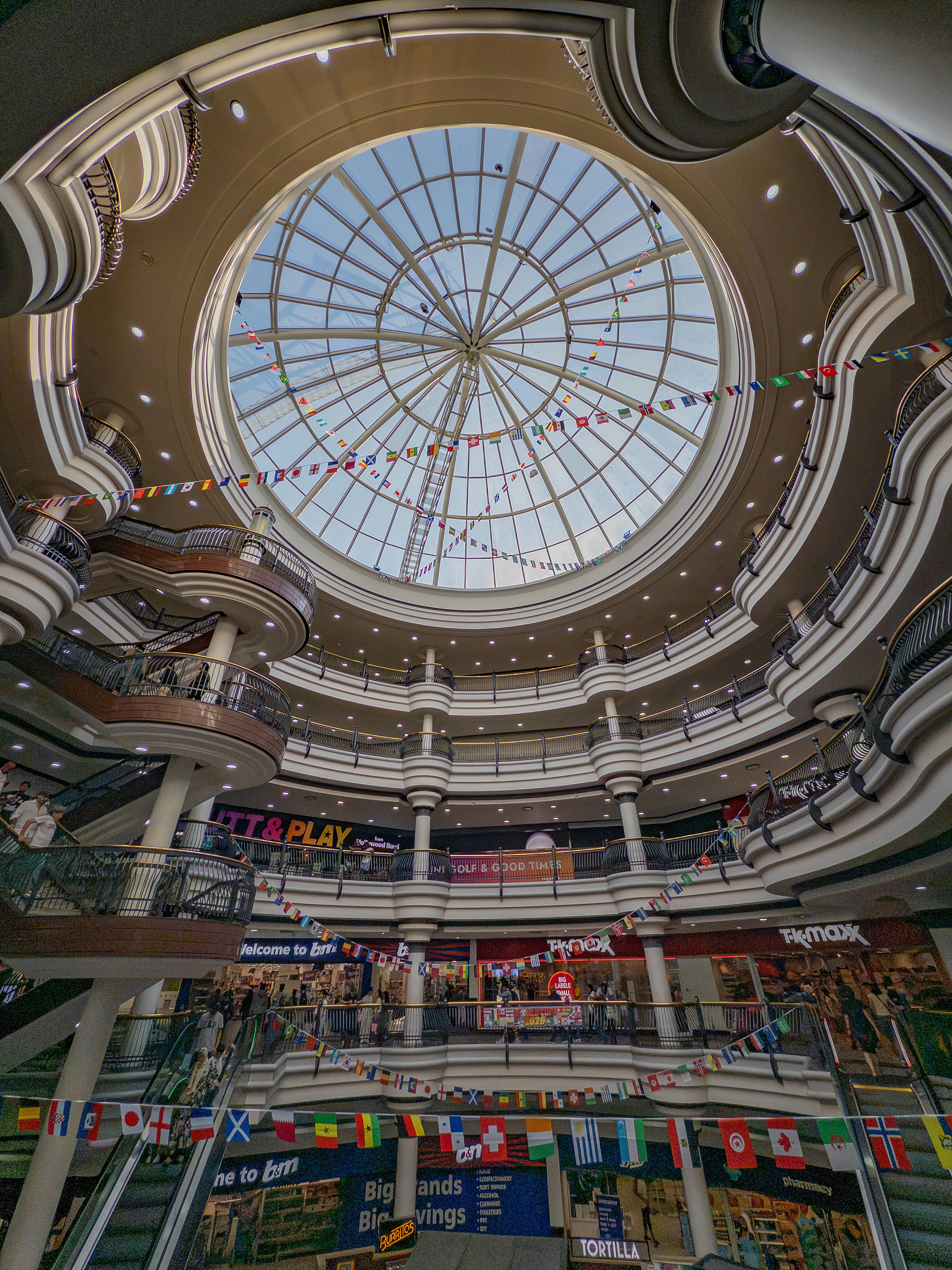 Multi-story shopping mall interior with a large glass dome.