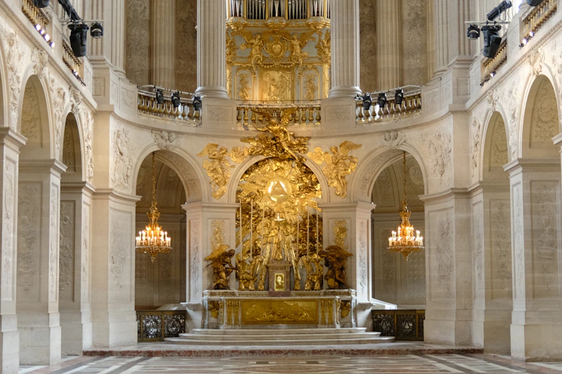 Ornate golden altar inside a grand, historic chapel with chandeliers
