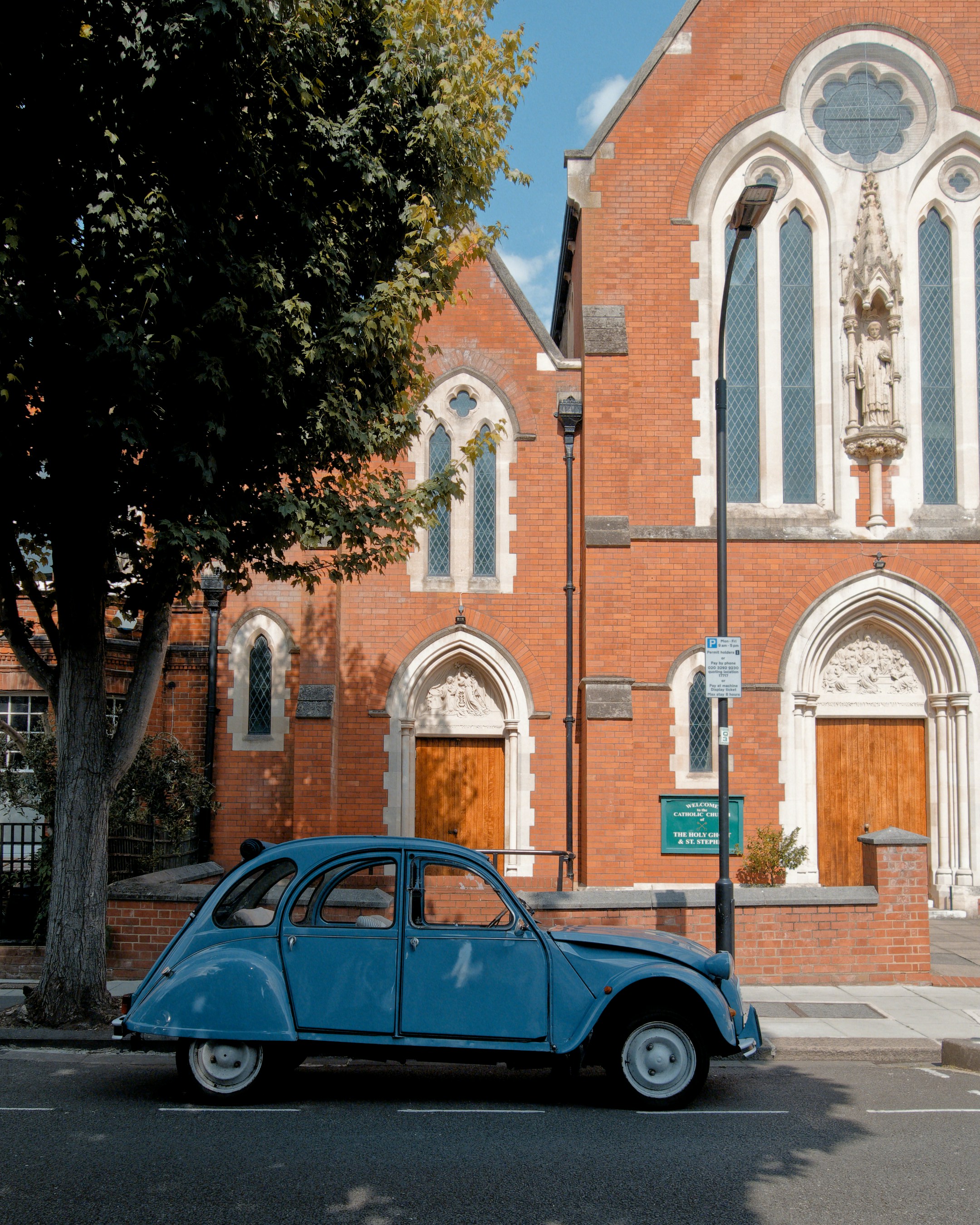 Classic blue car parked beside a red brick church