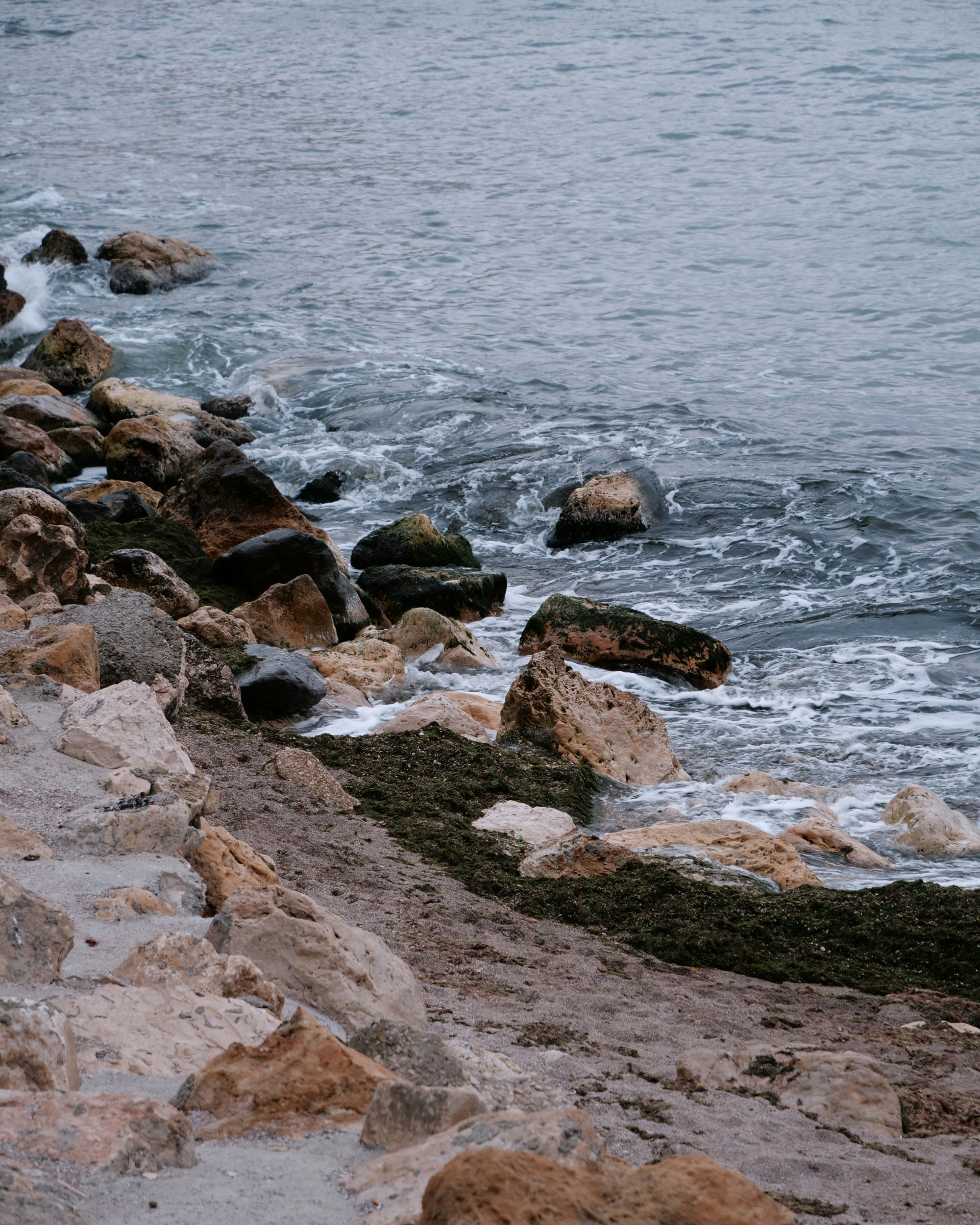 Waves crash against a rocky coastline on an overcast day
