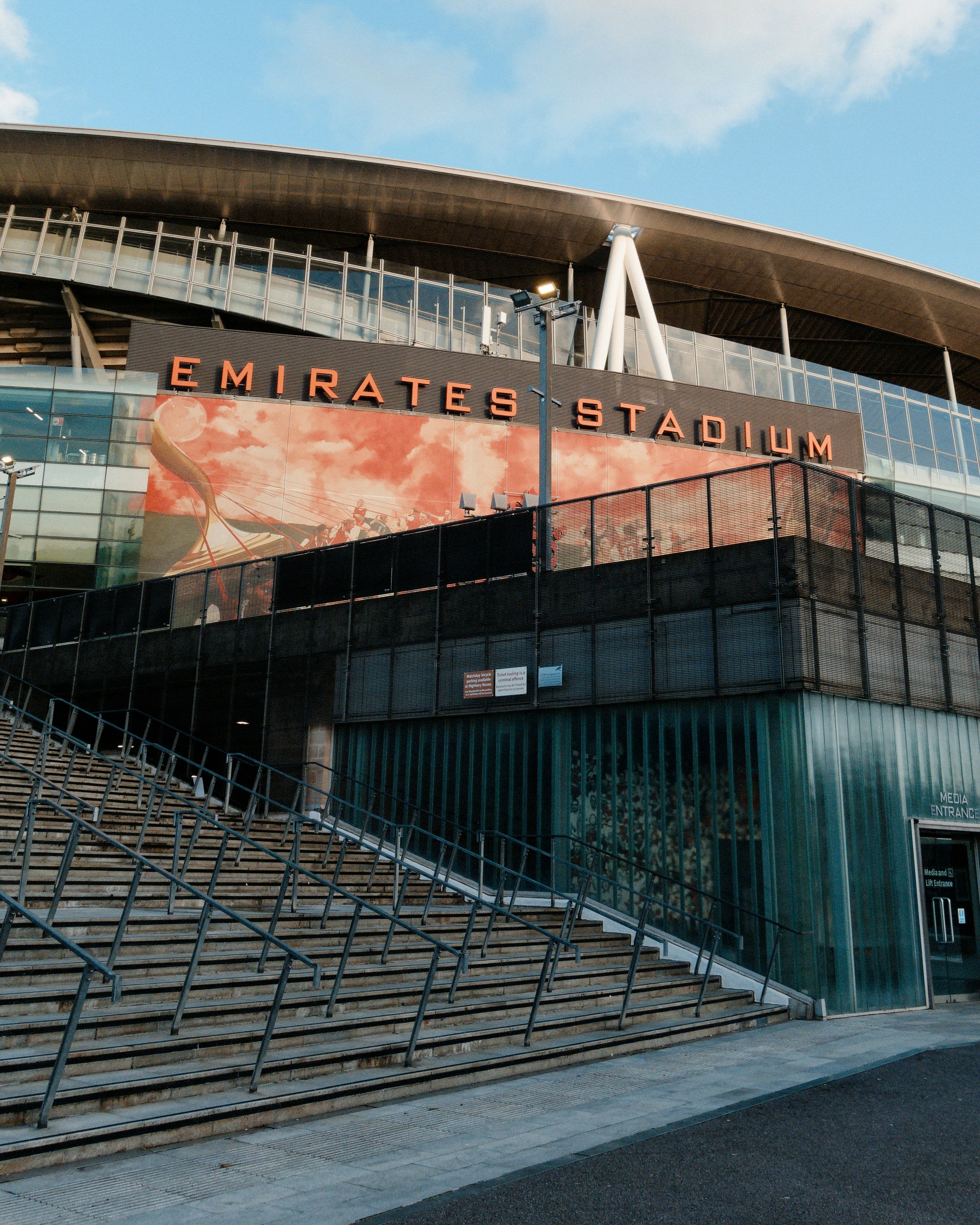 Emirates stadium facade and entrance stairs under a blue sky