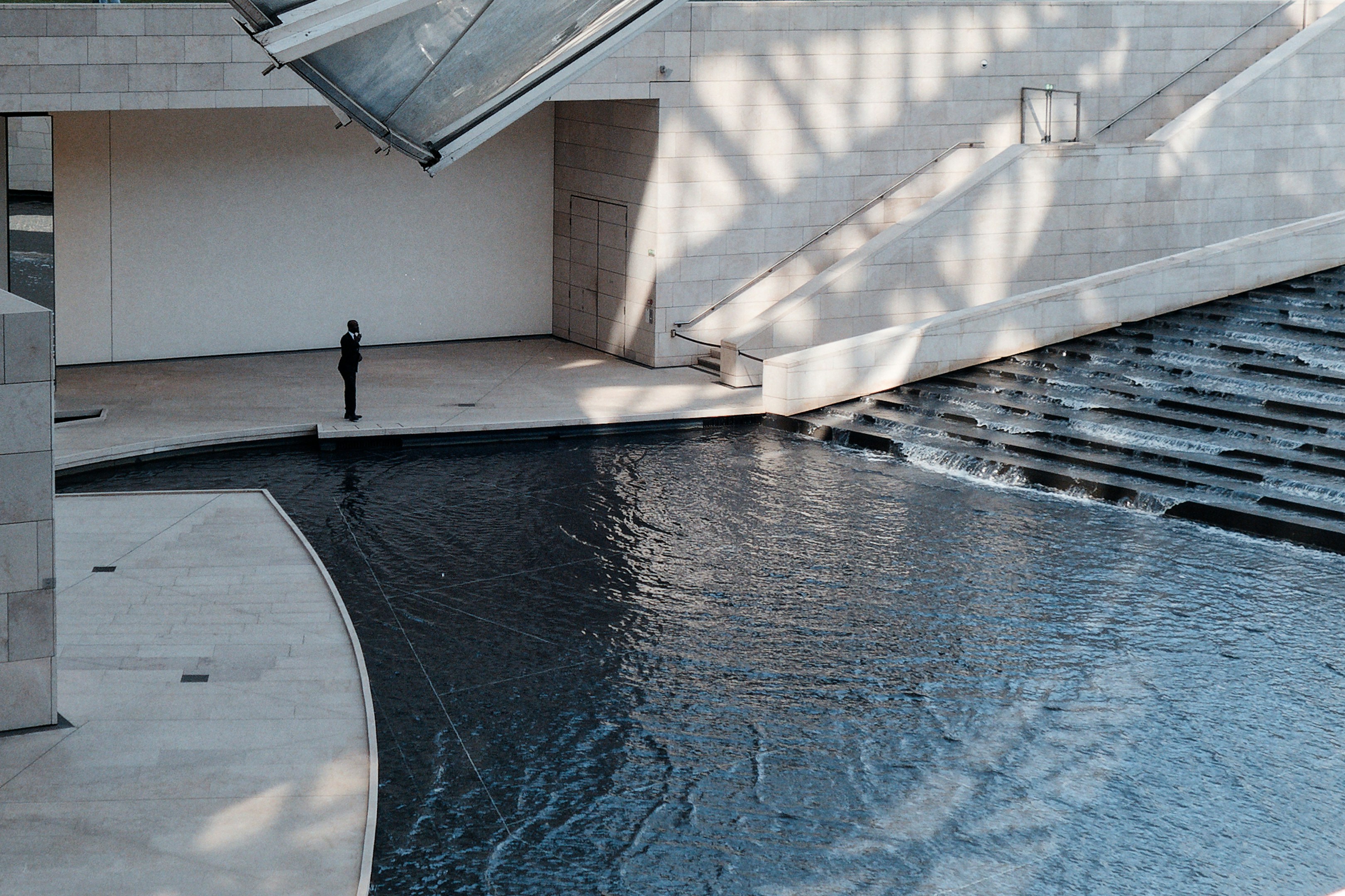 Person standing by modern building and flowing water