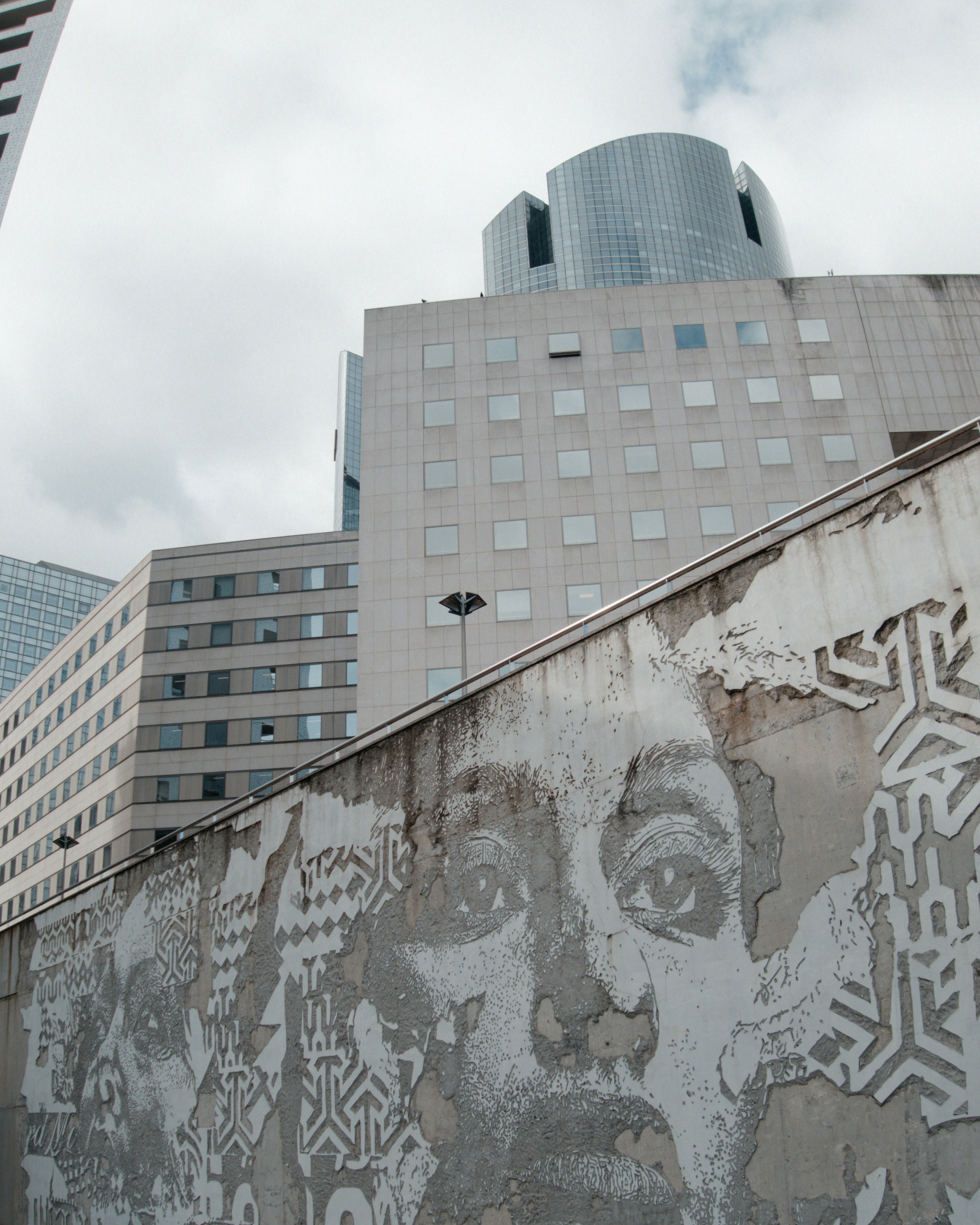 Graffiti of a face on a wall with modern buildings