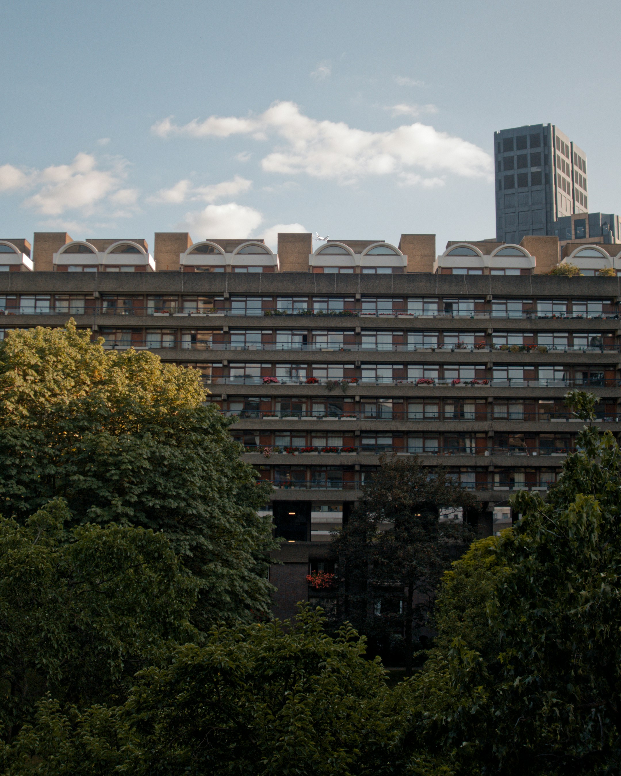 Brutalist architecture with green trees and a distant skyscraper