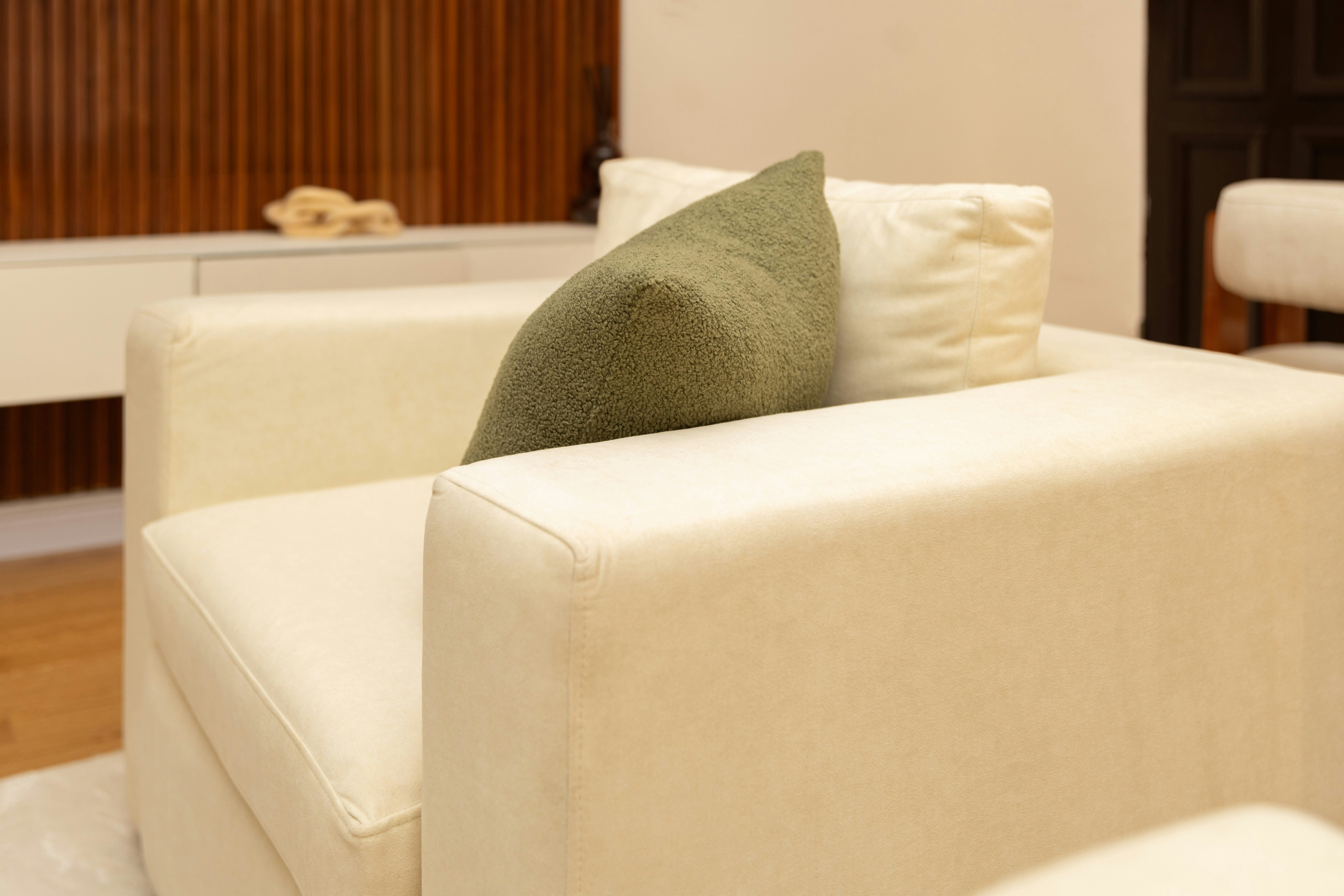 Modern white armchair with green and white pillows.