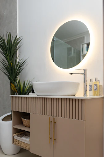 Mueble de baño moderno con espejo redondo iluminado y lavabo de sobreponer.