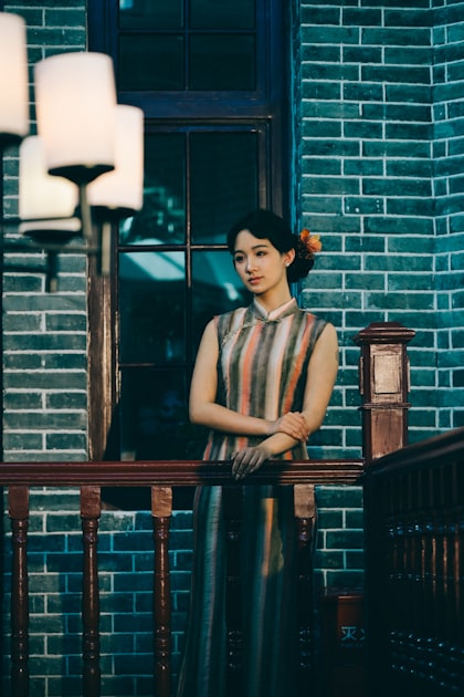 Elegant woman wearing cheongsam on a balcony, representing the connection between traditional Chinese dress culture and modern fashion