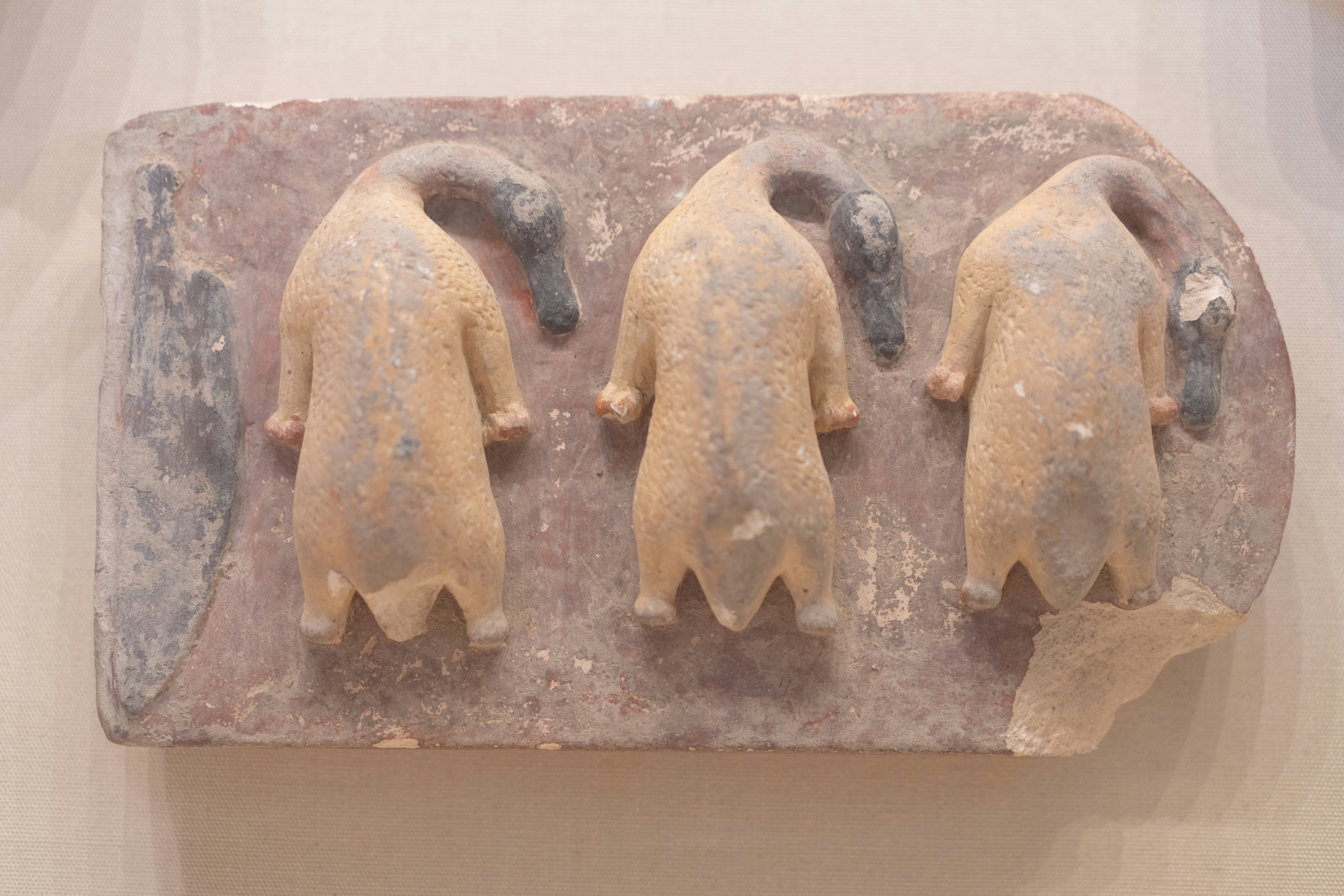 Trois figures anciennes stylisées sculptées sur une plaque de pierre