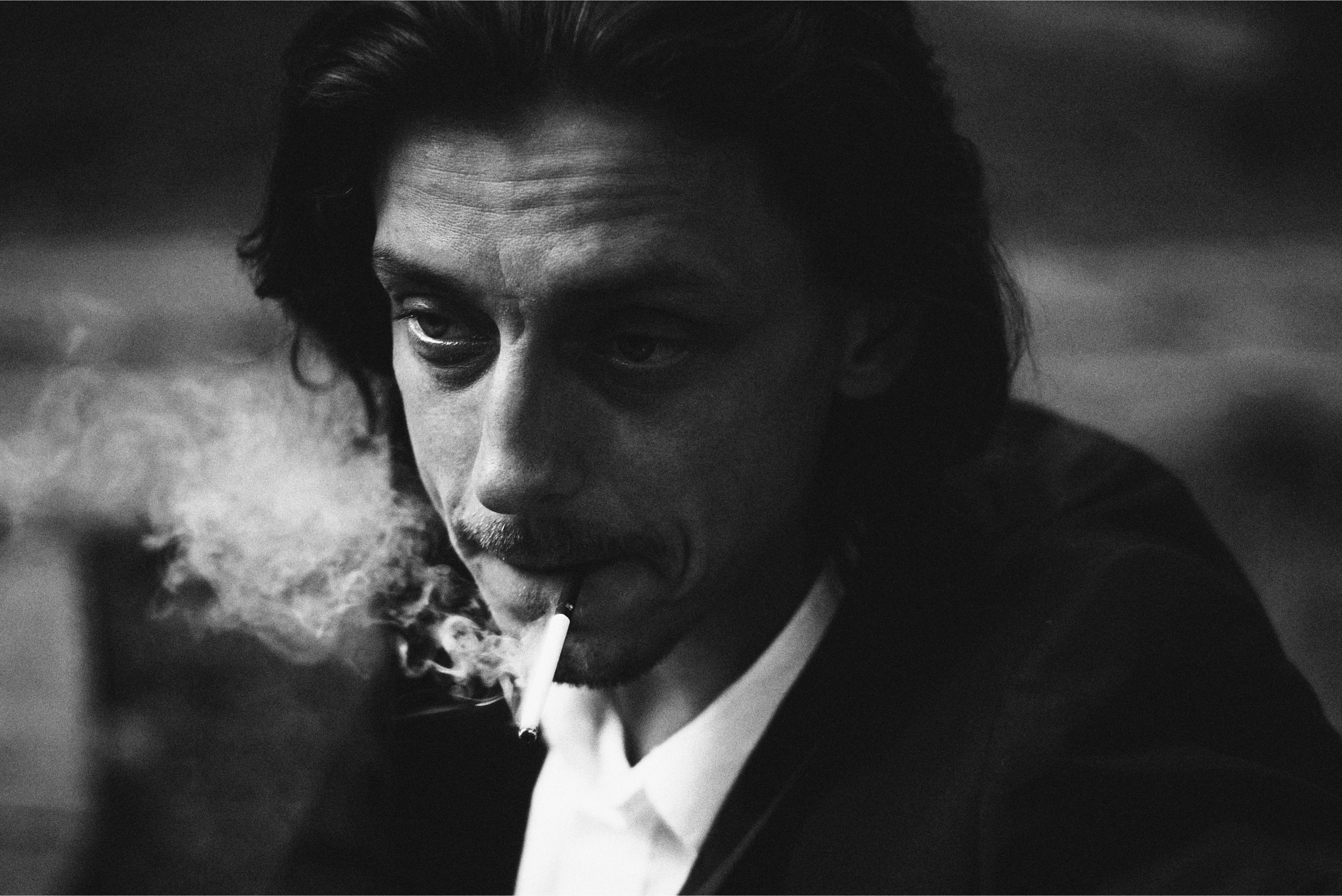 A man with long hair exhaling smoke.