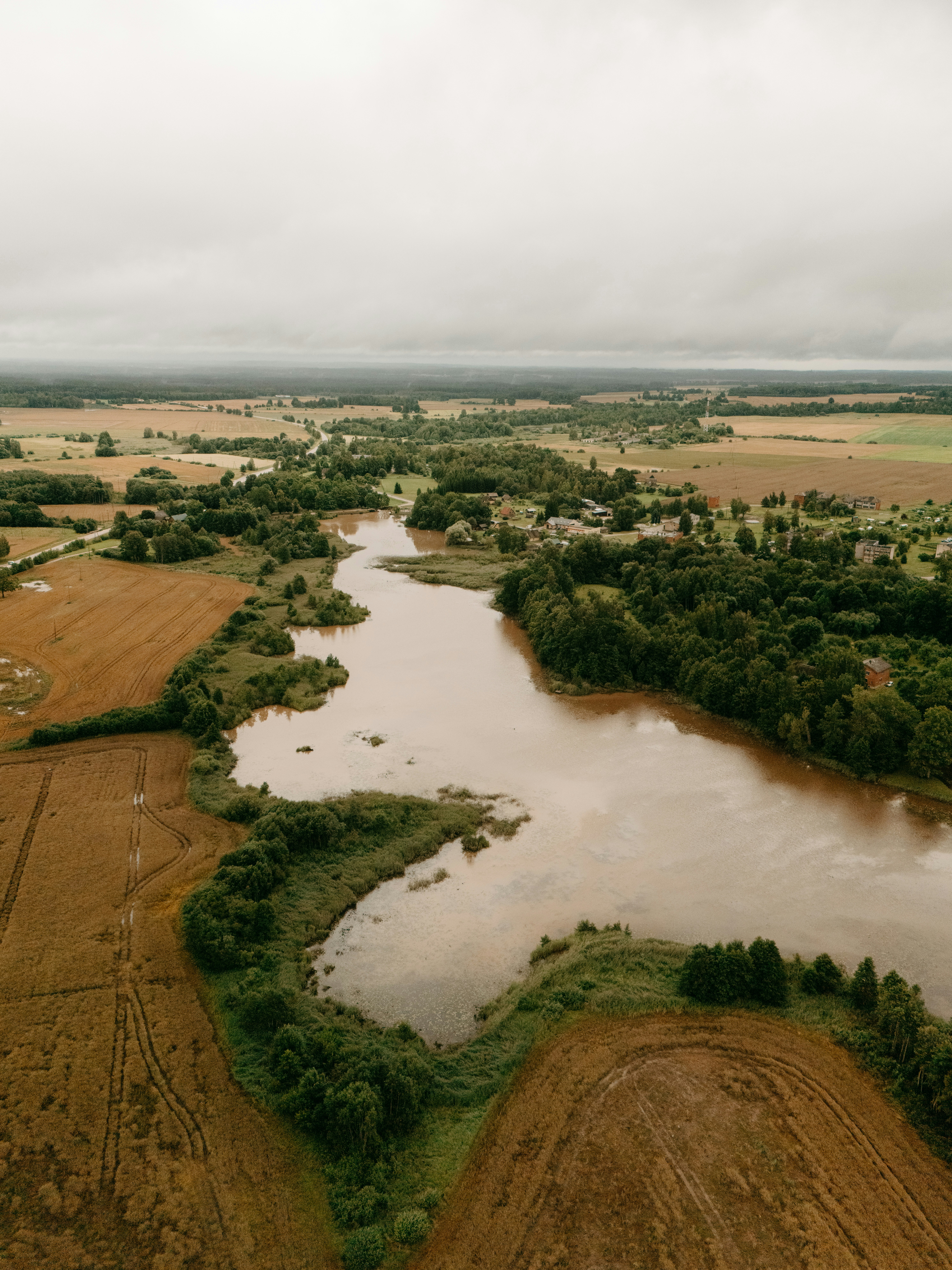 Aerial view of a winding river through fields and forests