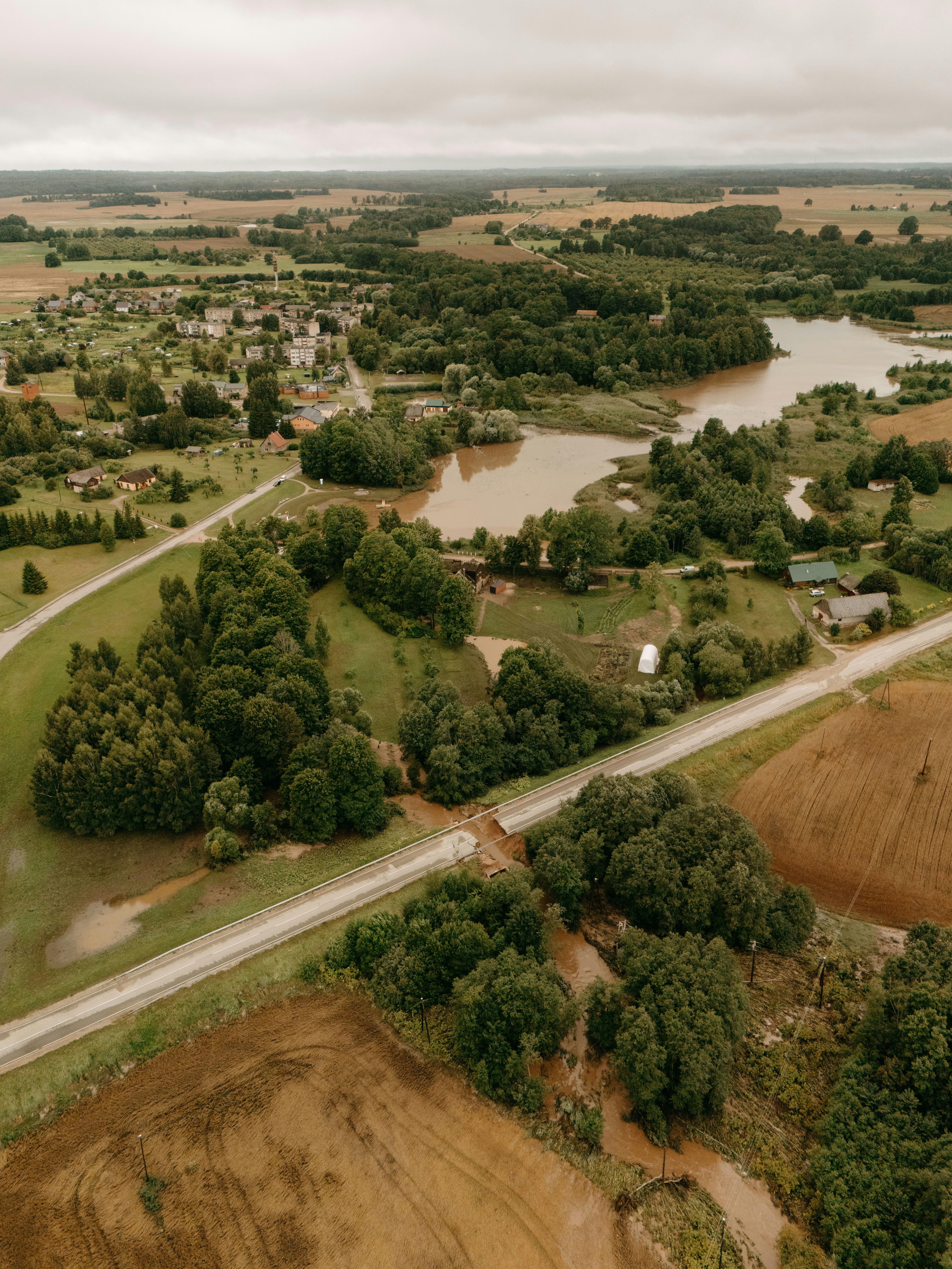 Rural landscape with fields, trees, road, and muddy river