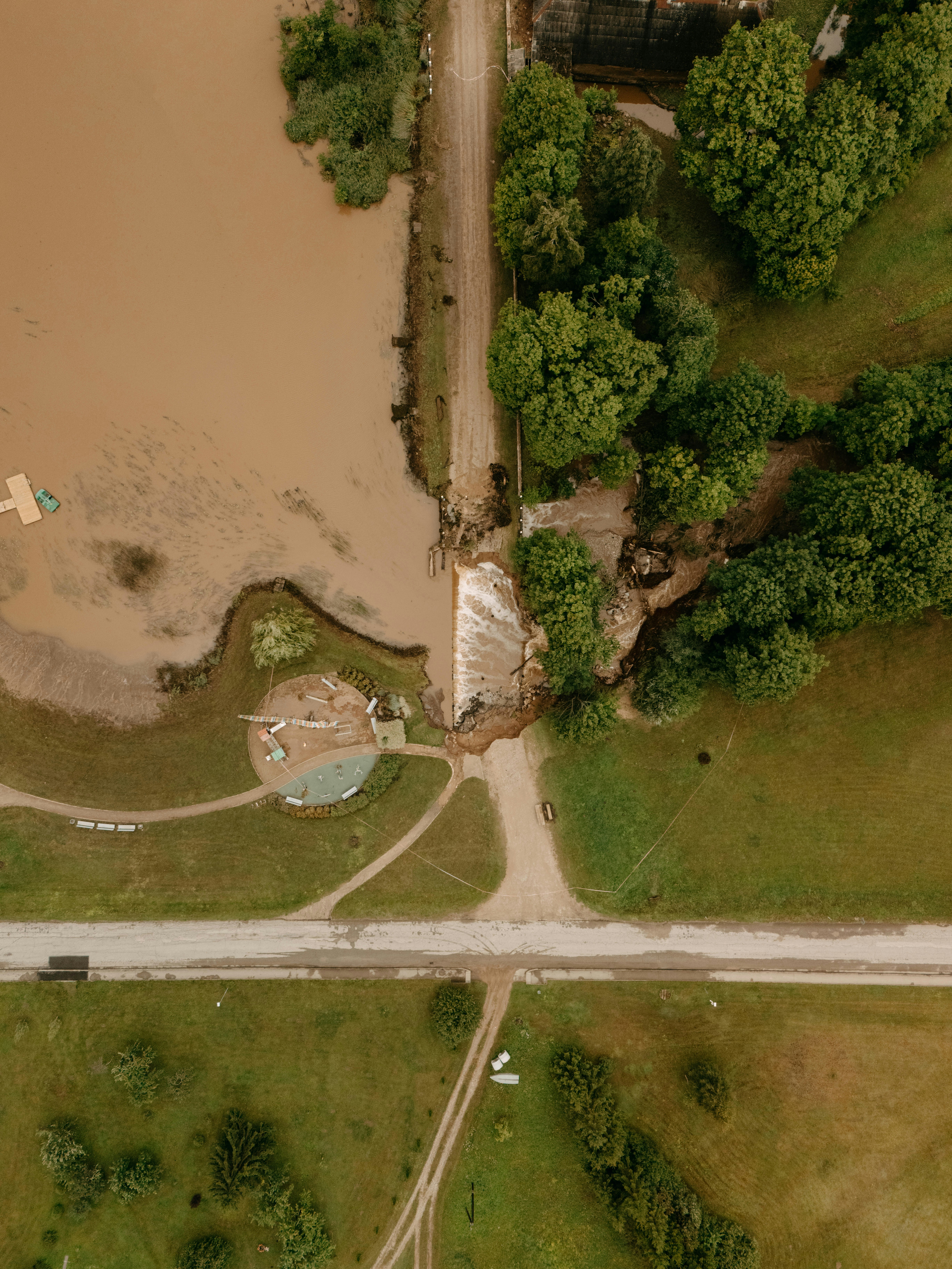 Aerial view of a muddy river overflowing a damaged road