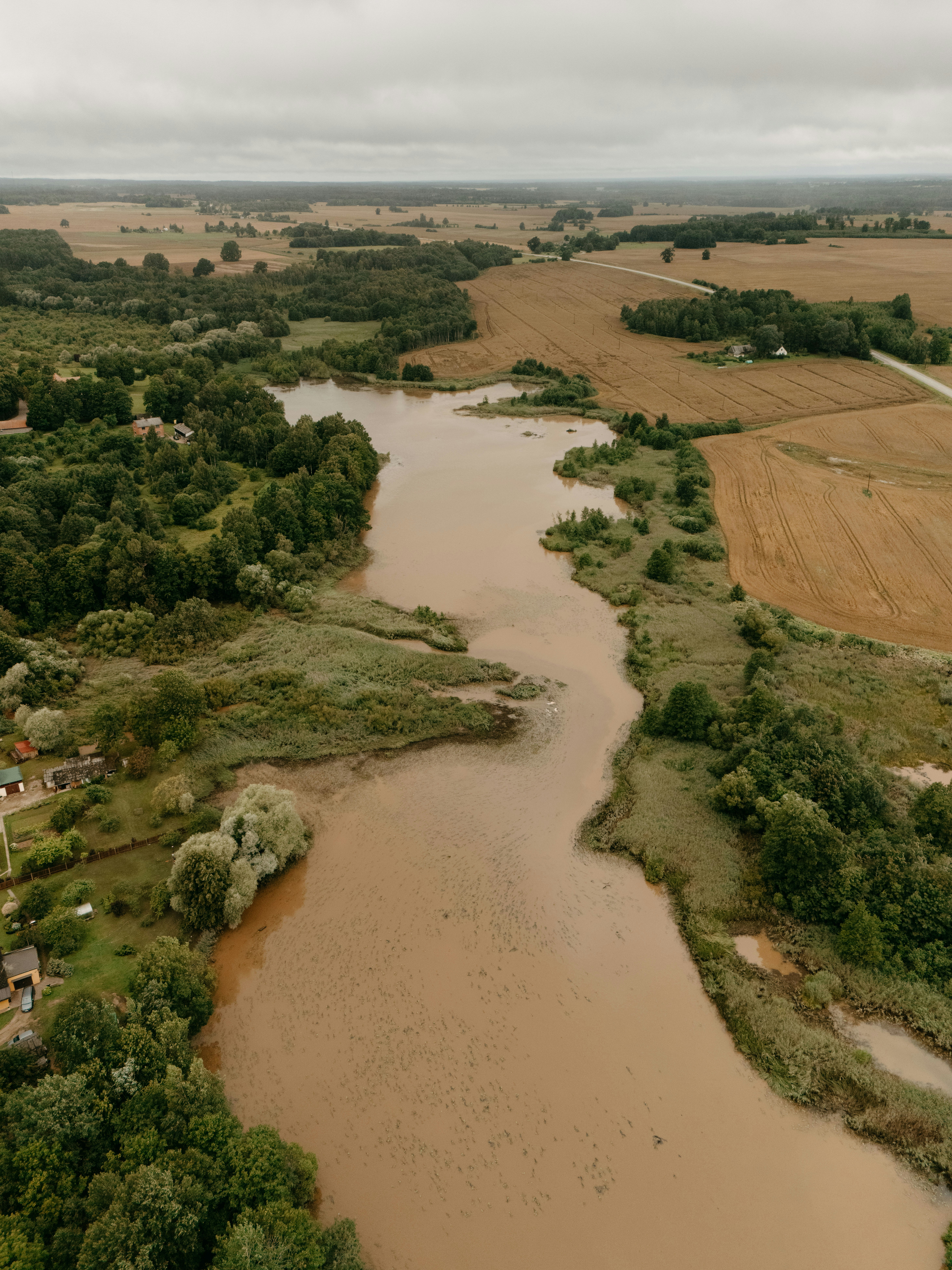 Winding river flows through green landscape under a cloudy sky