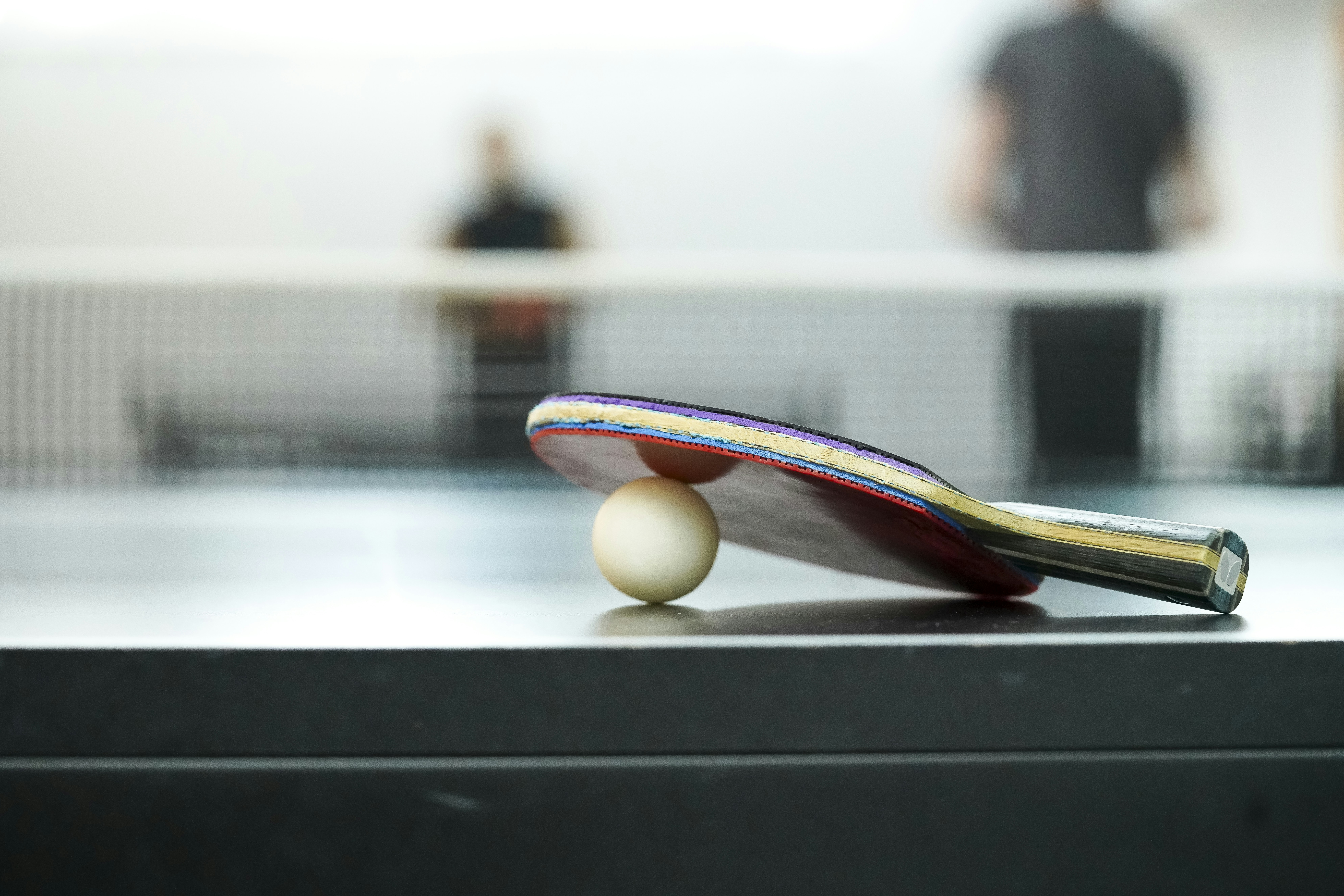 Ping pong paddle and ball on a black table