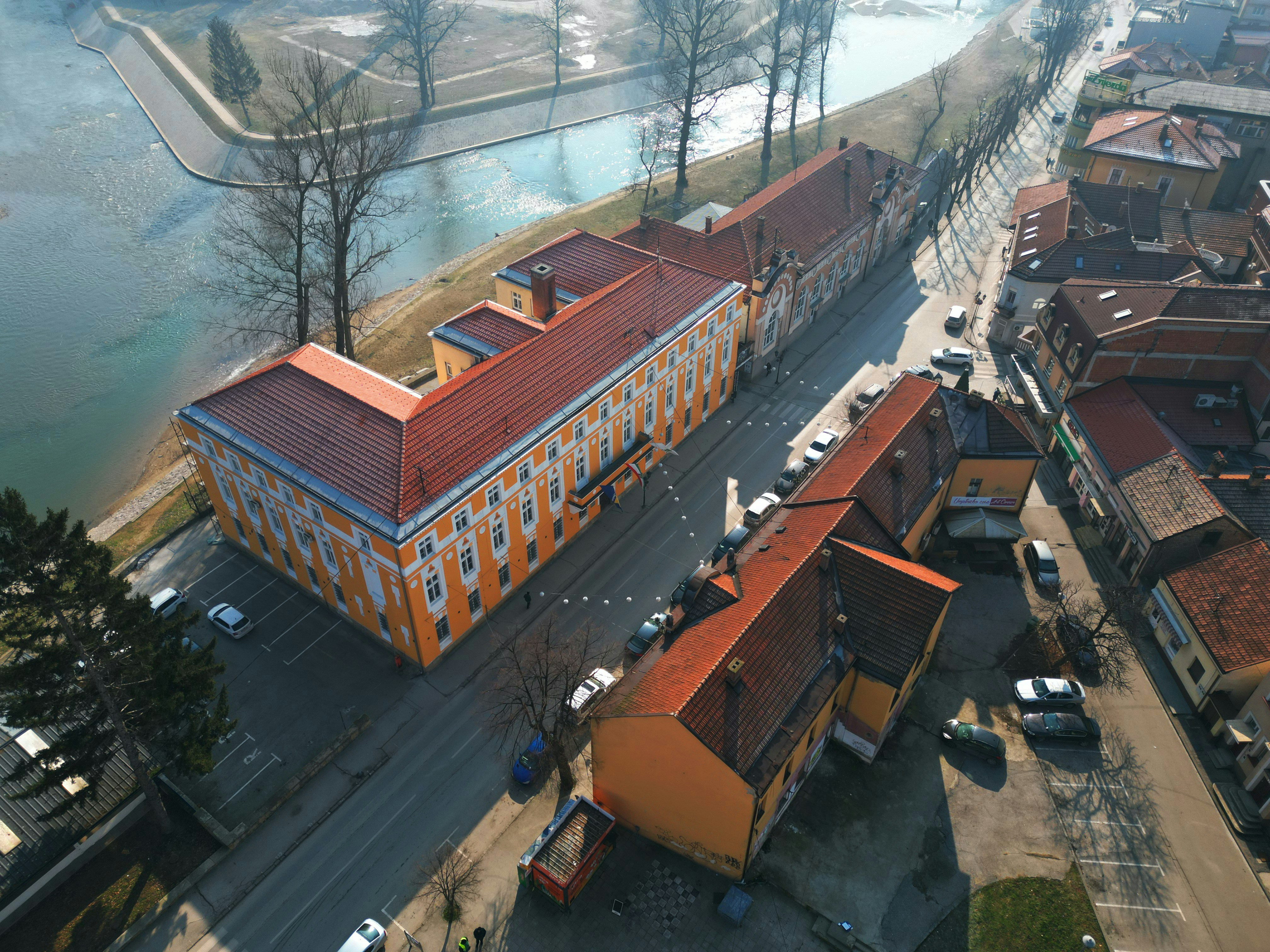 Aerial view of orange-roofed buildings alongside a river.