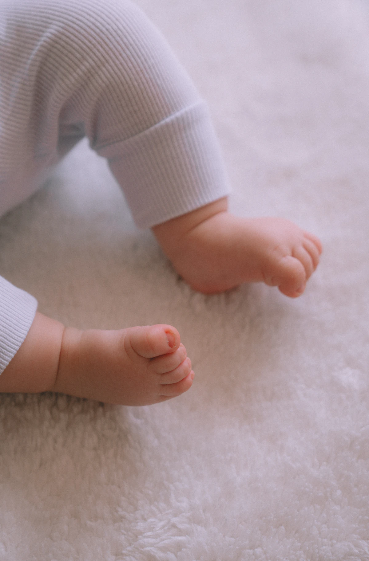 Kaki bayi mungil di atas selimut putih lembut