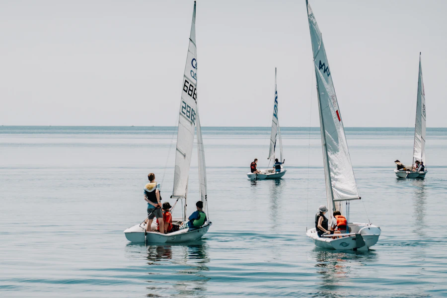 Small sailboats with crew on calm blue water, beginner sailing class