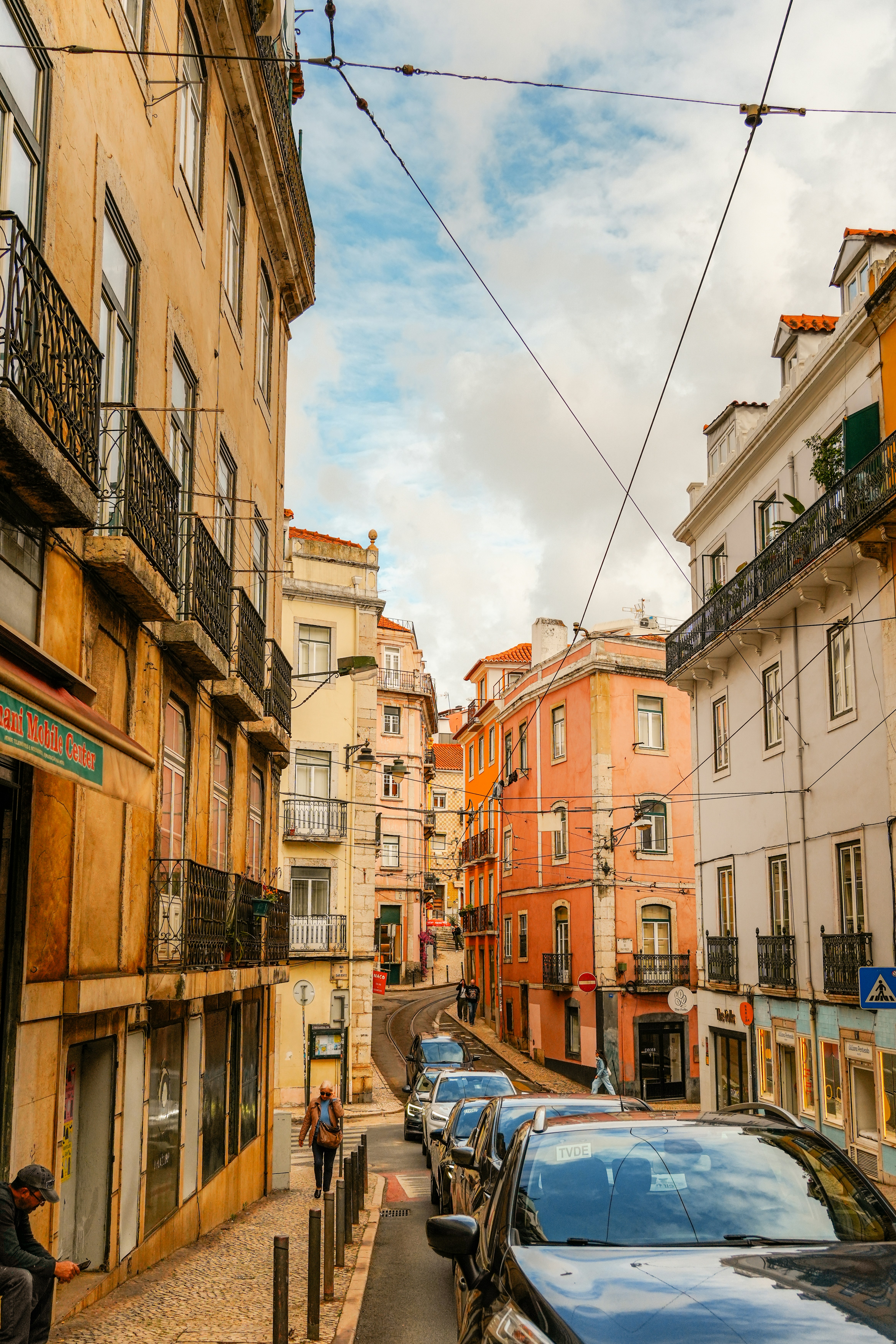 A narrow street lined with colorful buildings and parked cars