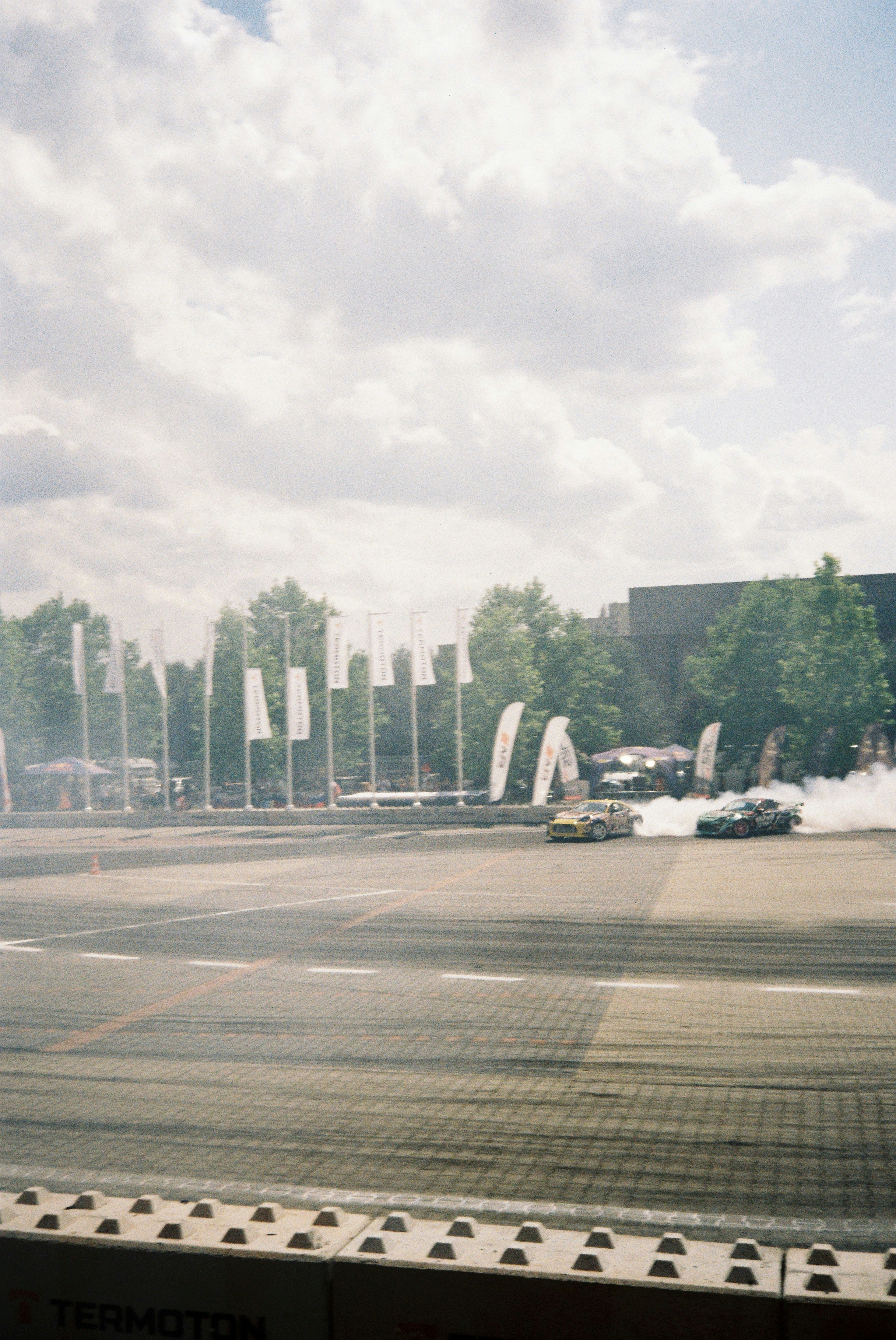 Two cars drifting with smoke on a paved track