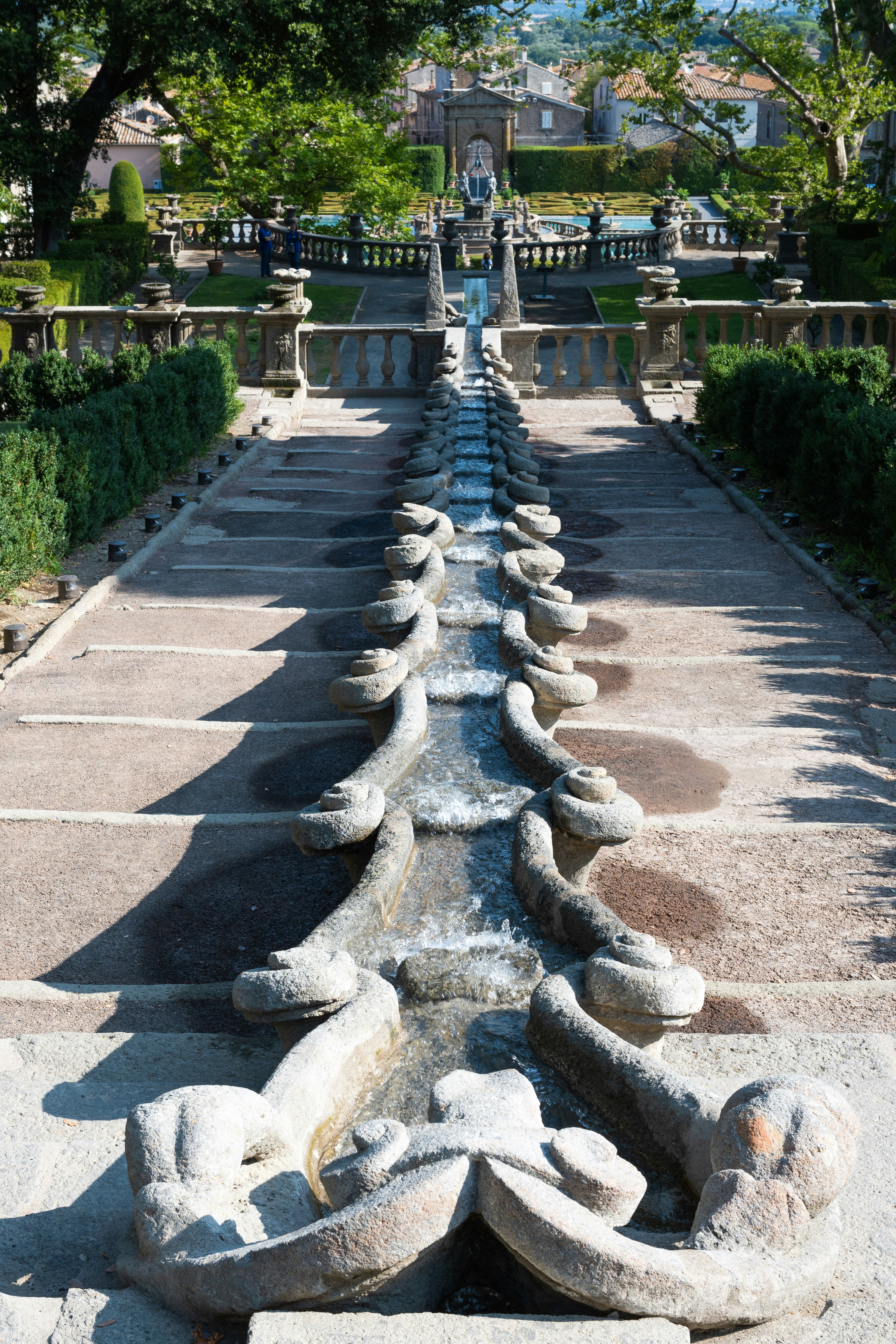 Ornate stone staircase with cascading water feature leading to building.