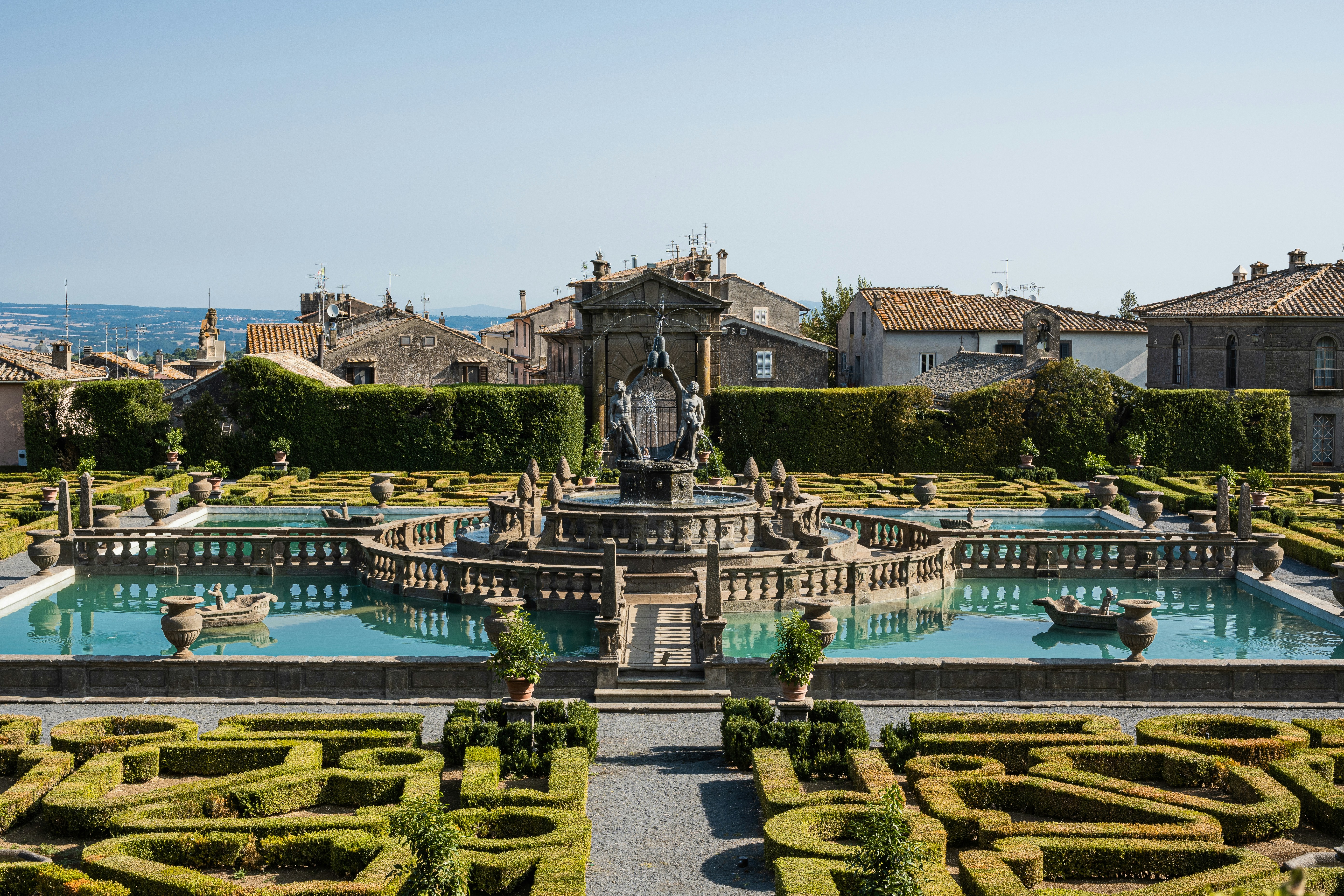 An ornate italian garden with fountains, pools, and manicured hedges.