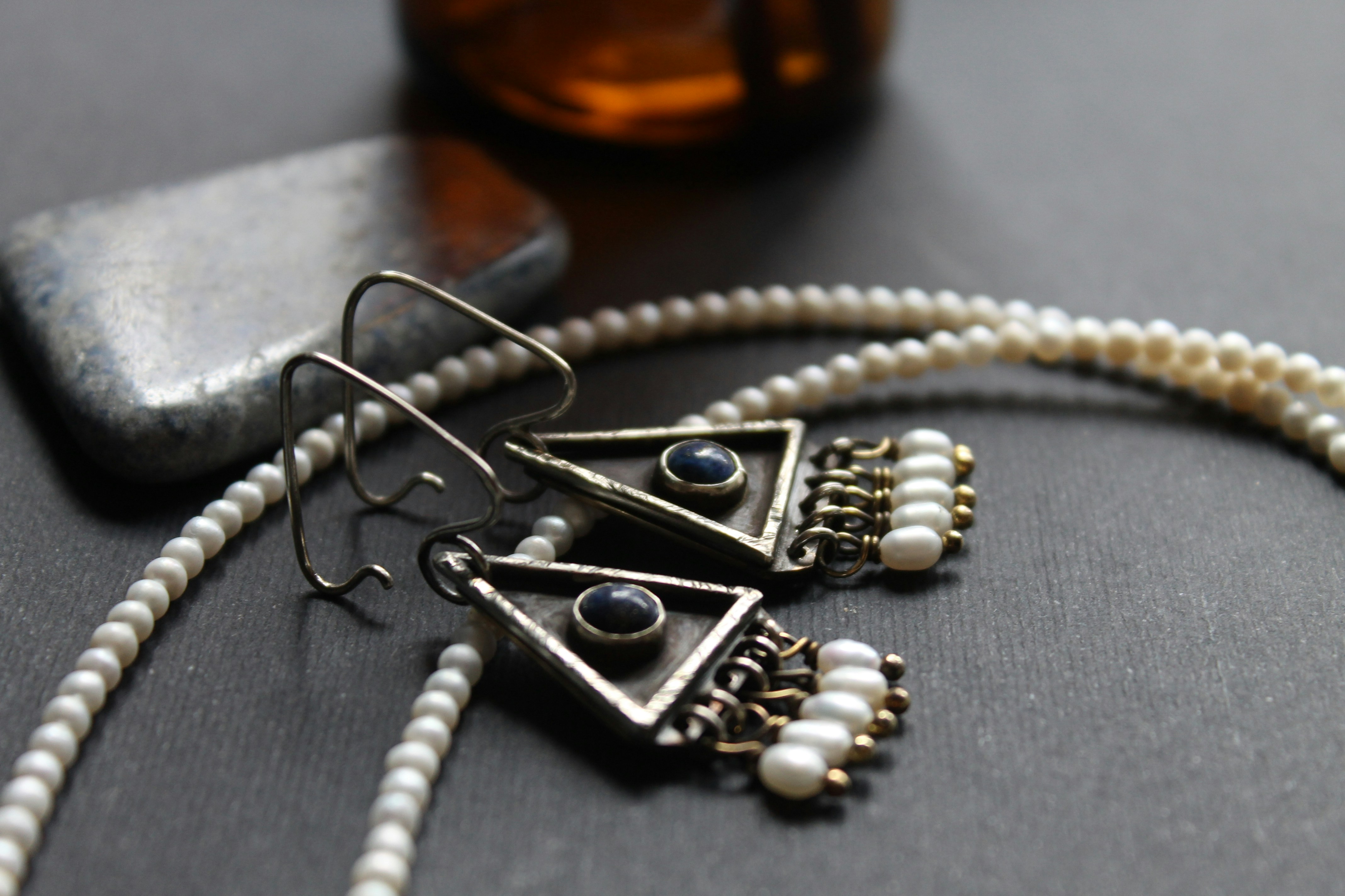 Boucles d’oreilles en argent et collier de perles sur une surface sombre