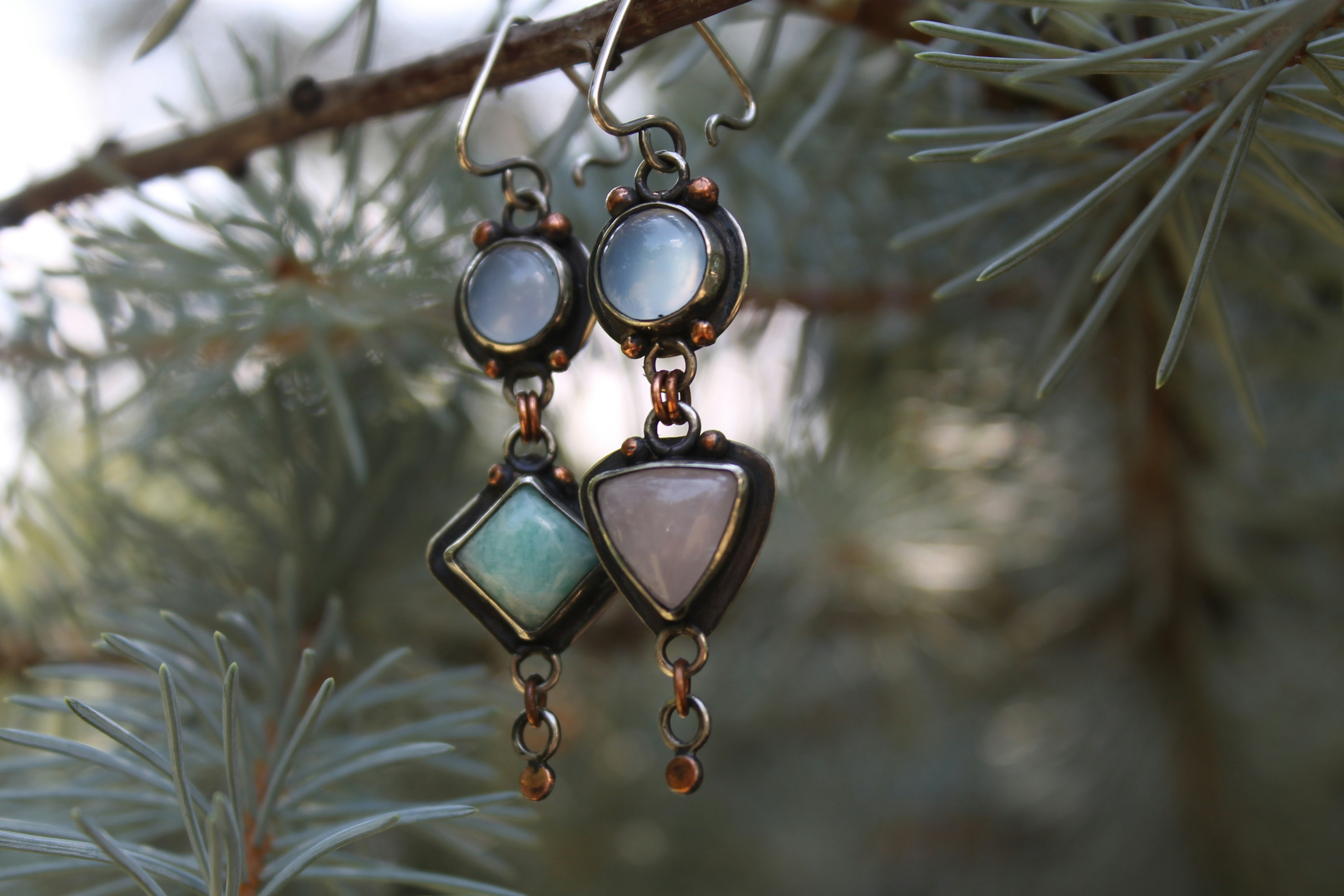 Boucles d’oreilles artisanales avec diverses pierres suspendues à une branche d’arbre