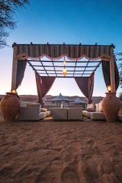 Ornate desert canopy with seating and lanterns at dusk