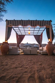 Ornate desert canopy with seating and lanterns at dusk