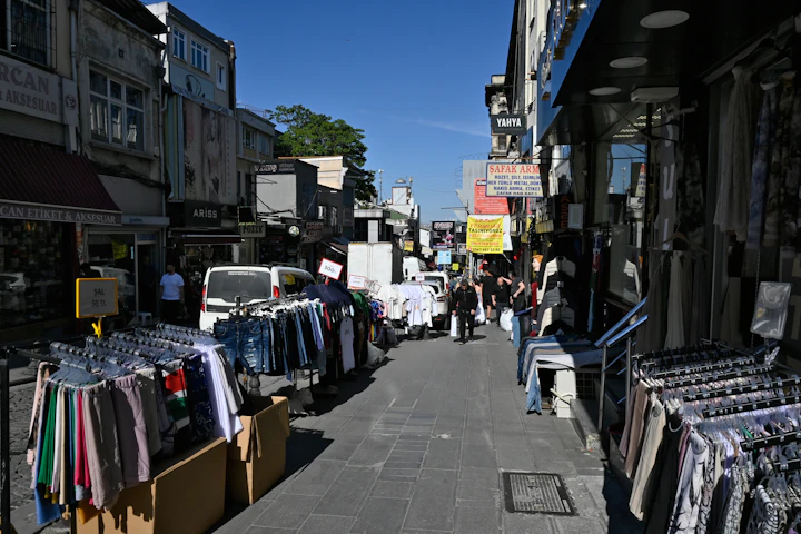 Narrow street lined with clothing racks and people shopping