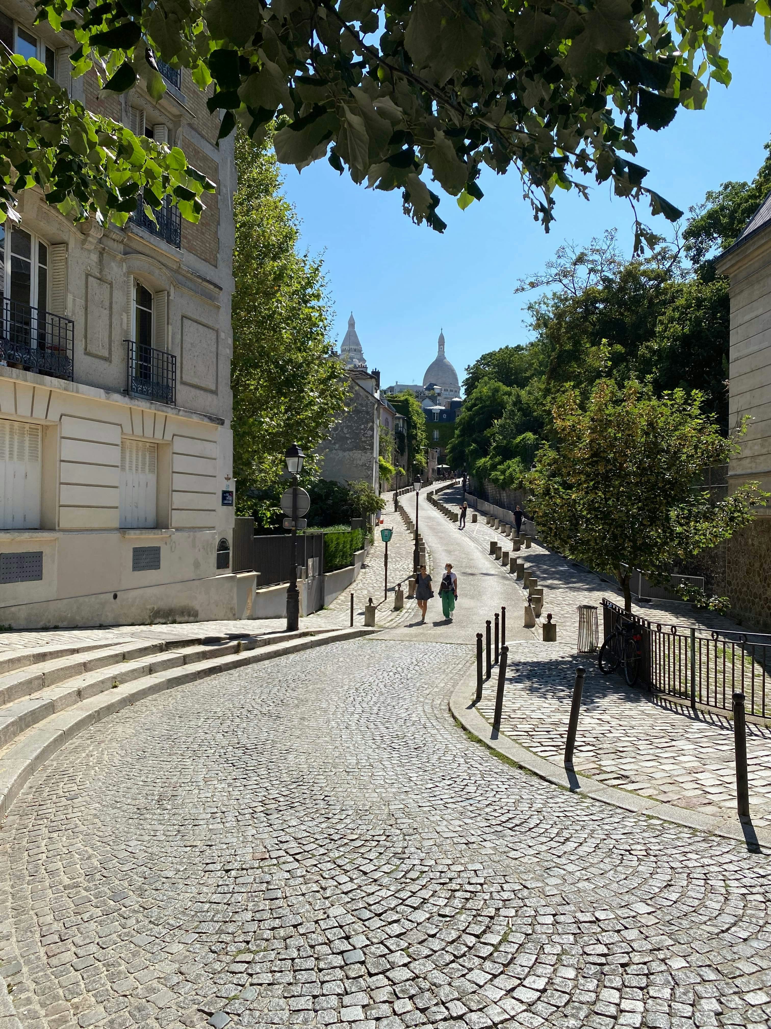Cobblestone street ascending towards a distant basilica in sunlight - montmartre essential sights hidden