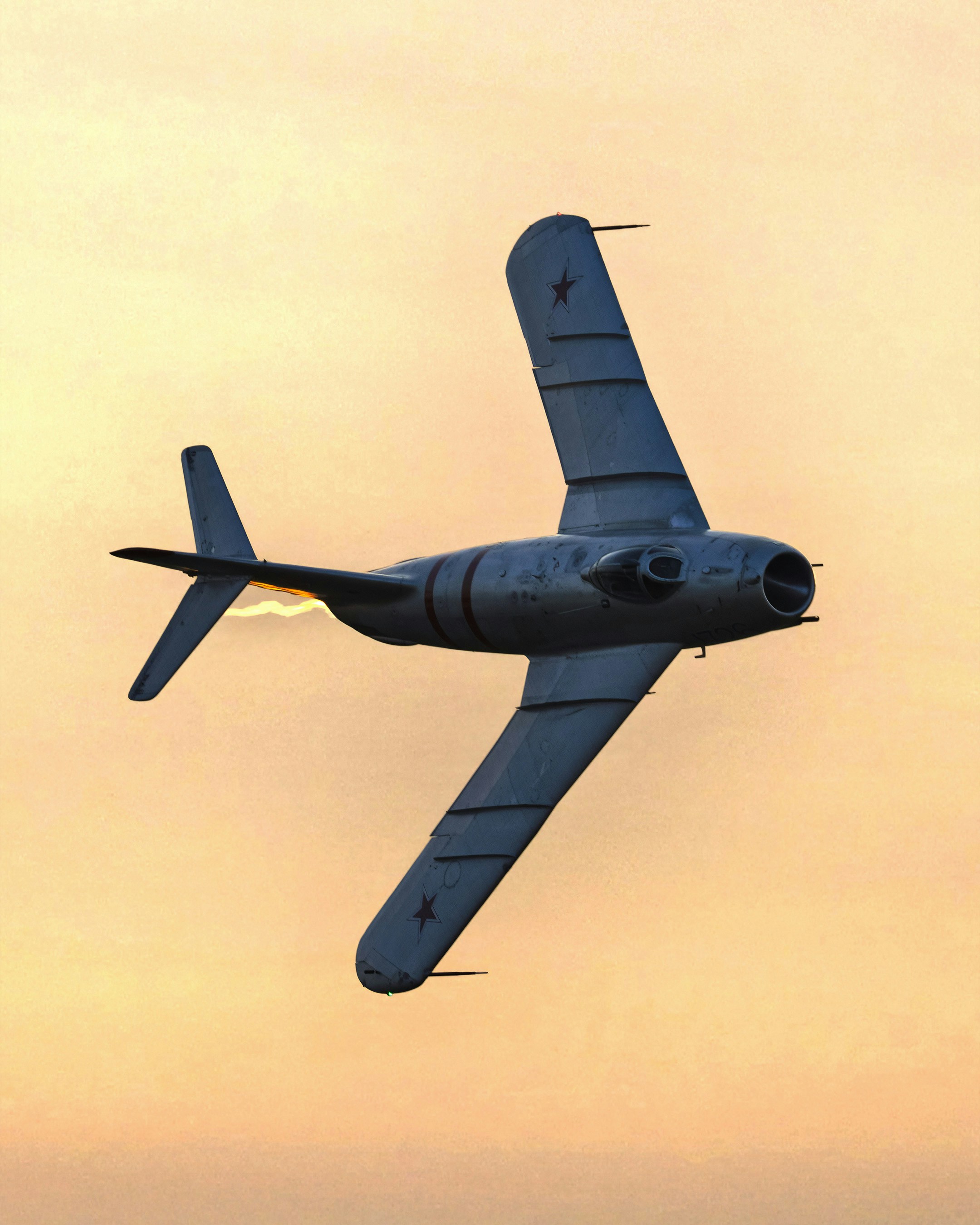 Un avion de chasse à réaction volant contre un ciel doré.