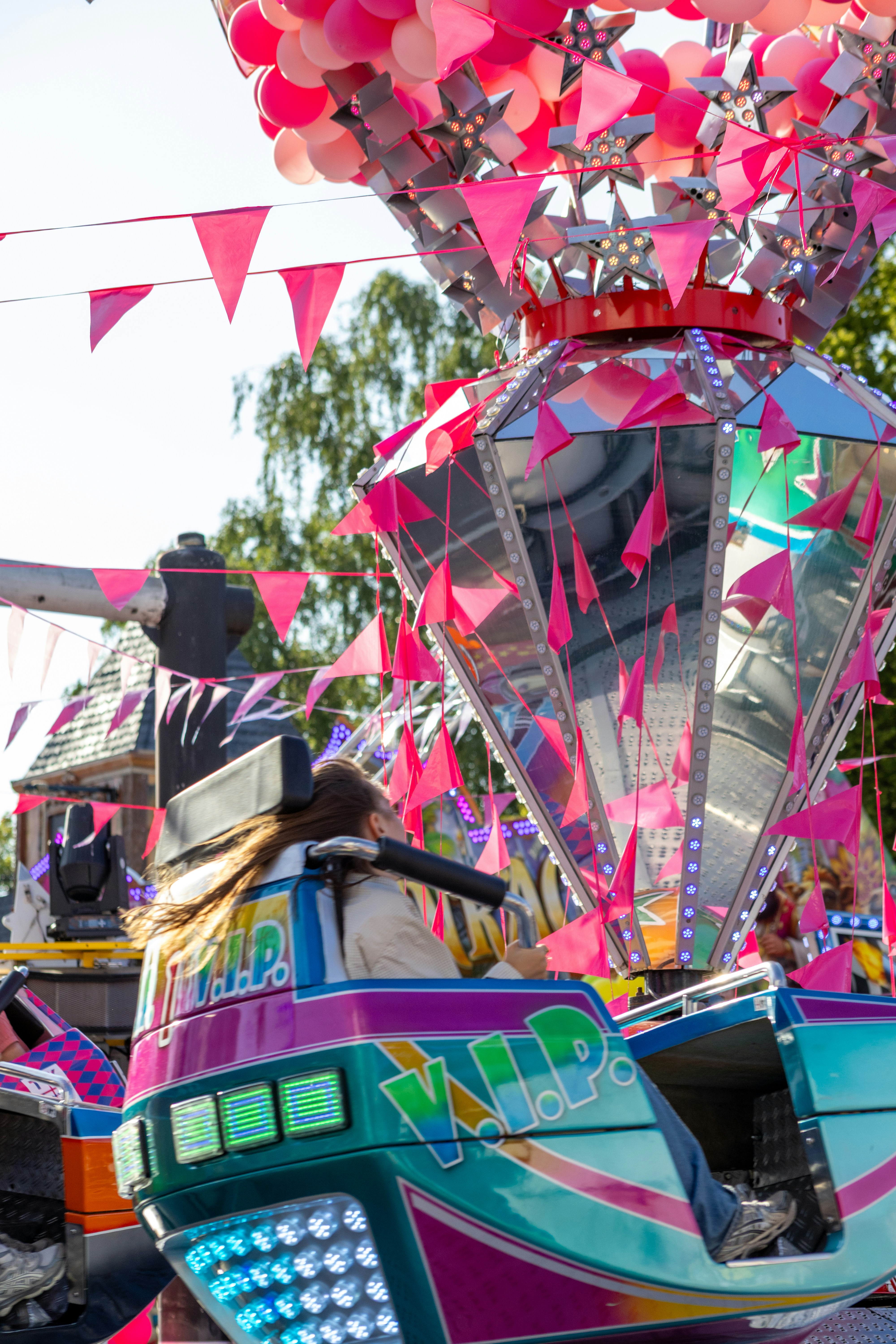 A person on a colorful carnival ride with pink decorations.