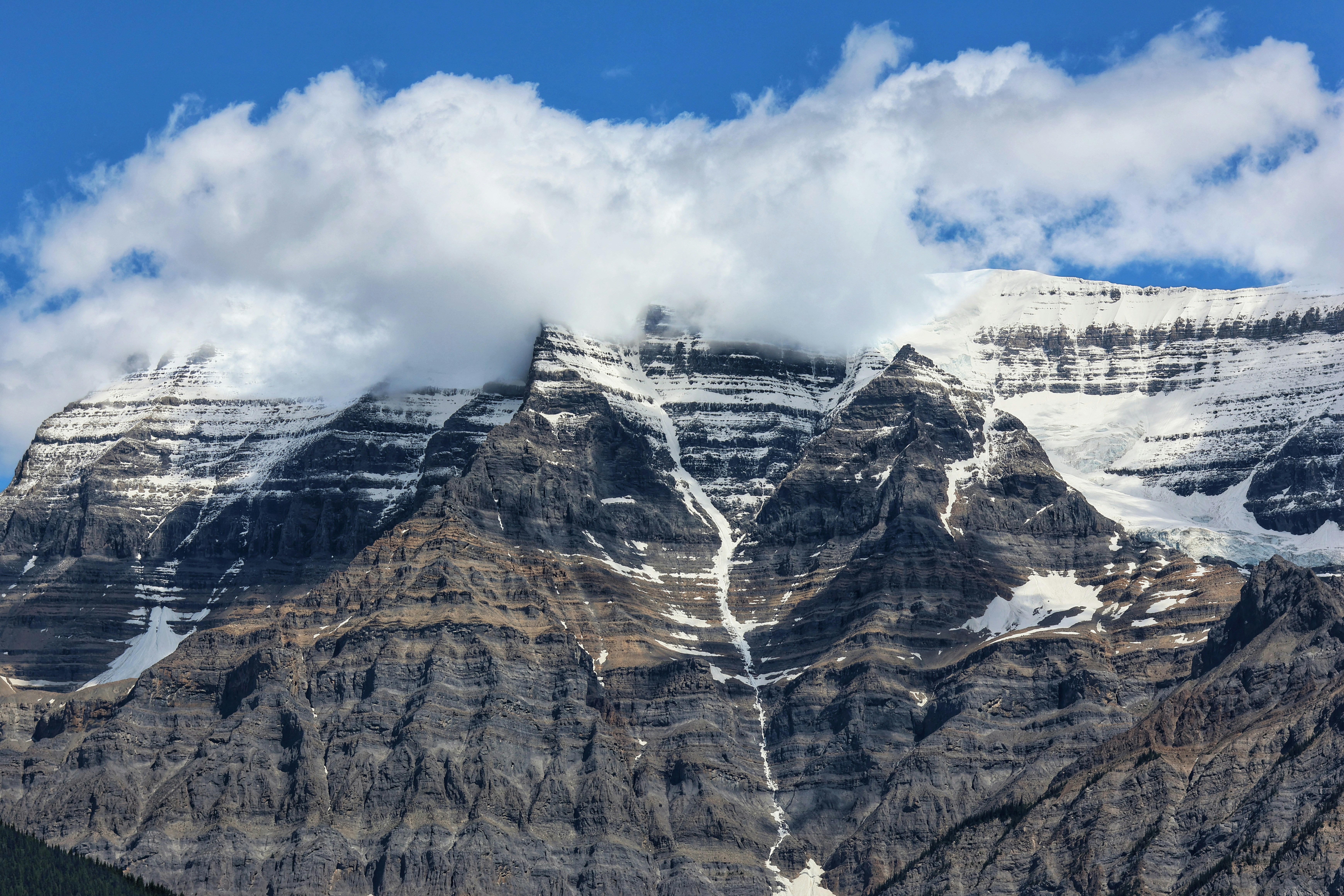 Schneebedeckte Berge mit Wolken unter blauem Himmel