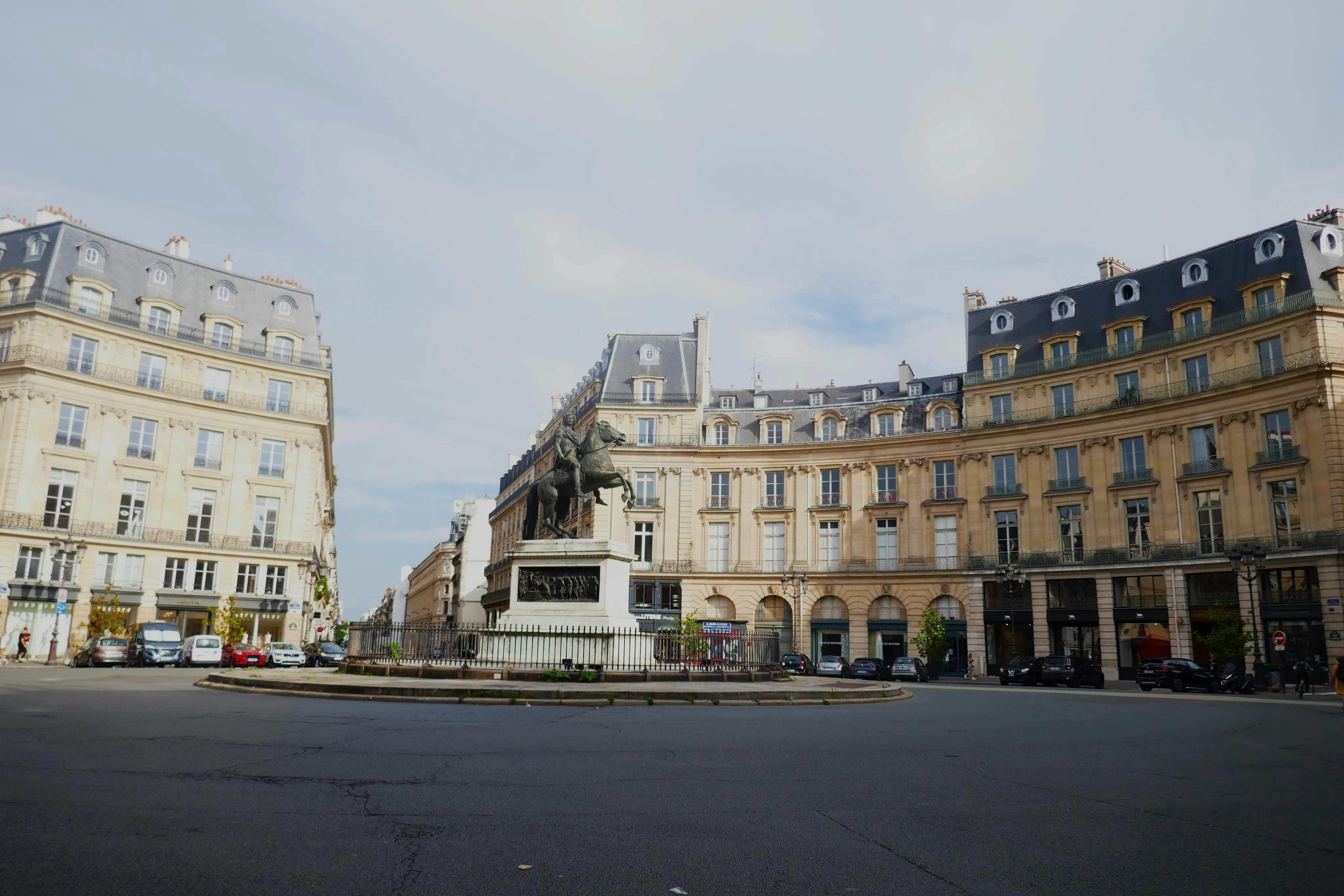 Historic buildings surround an empty city square with central m…