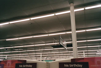 Fluorescent lights illuminate a retail store ceiling with signs