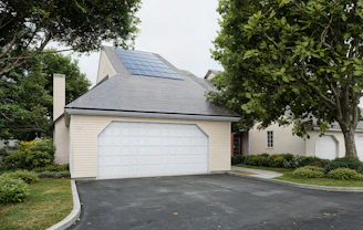 A house with solar panels, a garage, and green landscaping