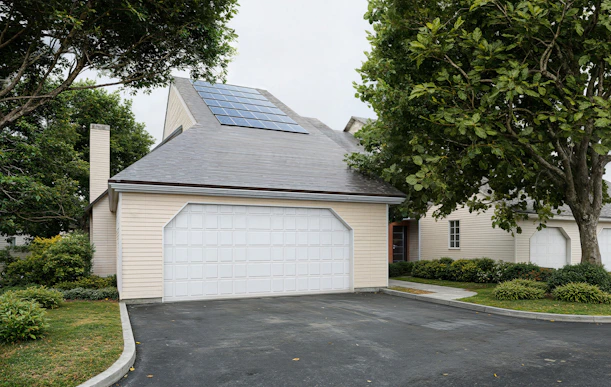 A house with solar panels, a garage, and green landscaping